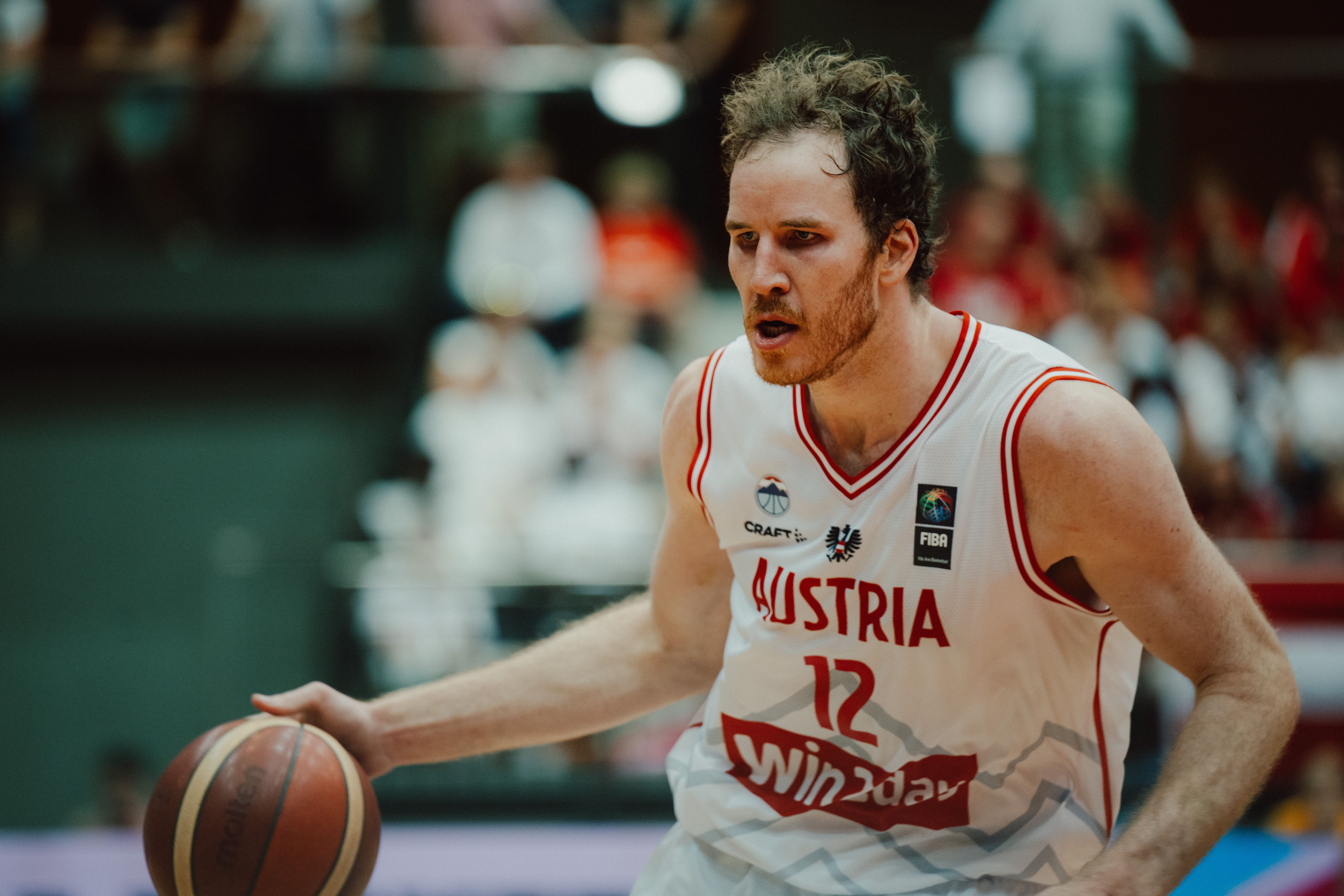 Ein Basketballspieler im Austria-Trikot dribbelt den Ball während eines Spiels.