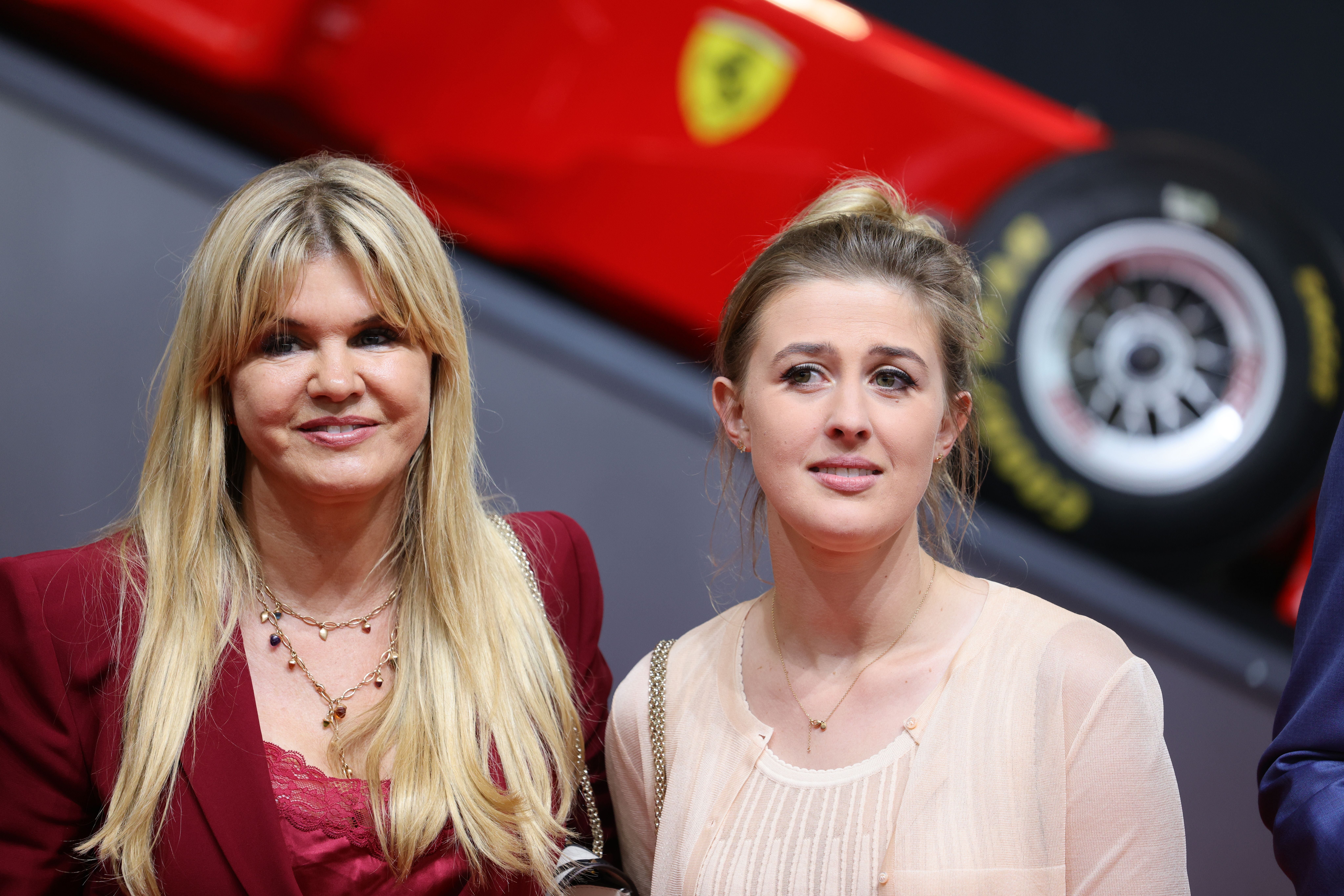 Zwei Frauen stehen nebeneinander vor einem roten Rennwagen.