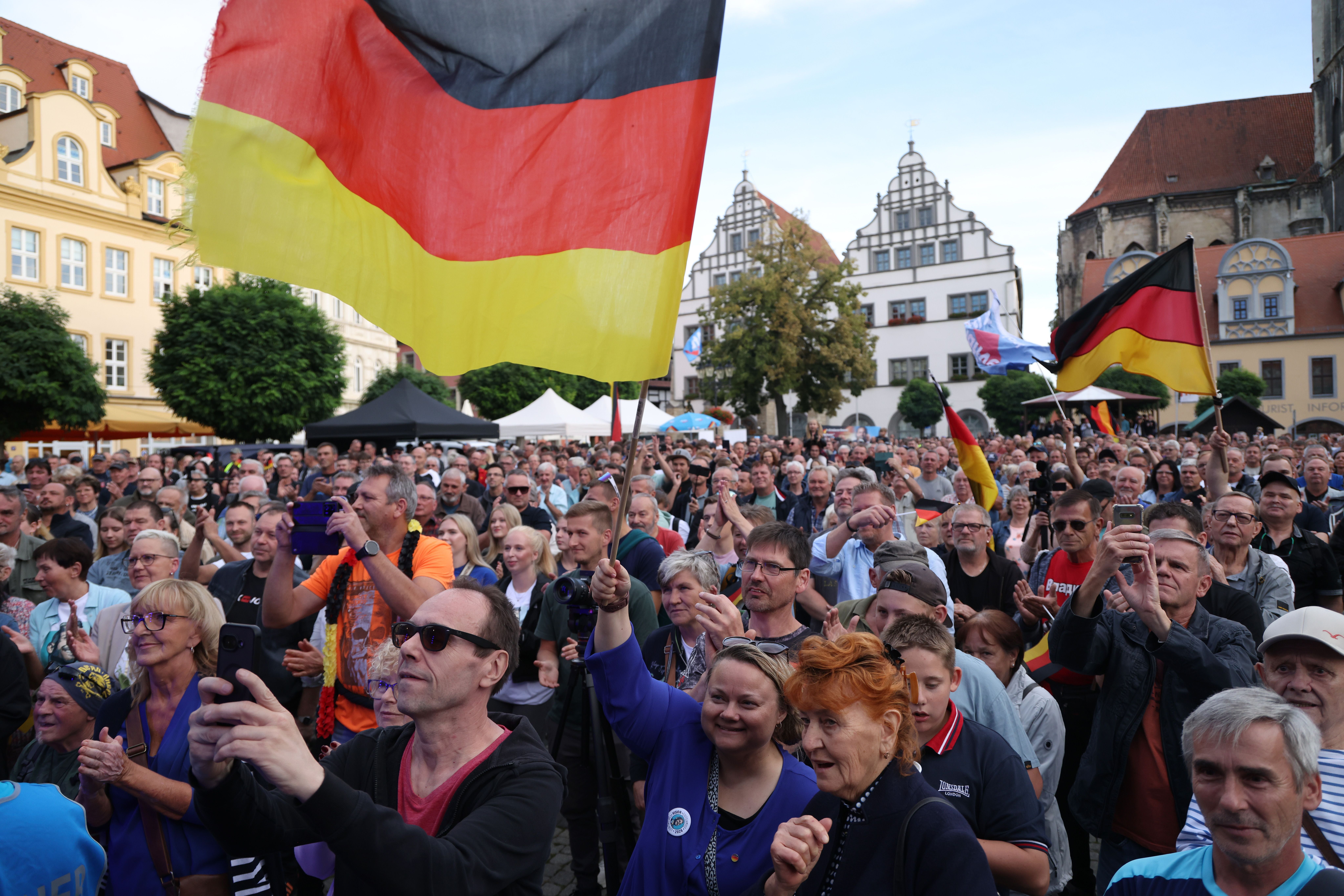Menschenmenge mit Deutschlandflaggen bei einer Kundgebung auf einem Platz in Naumburg, Deutschland.