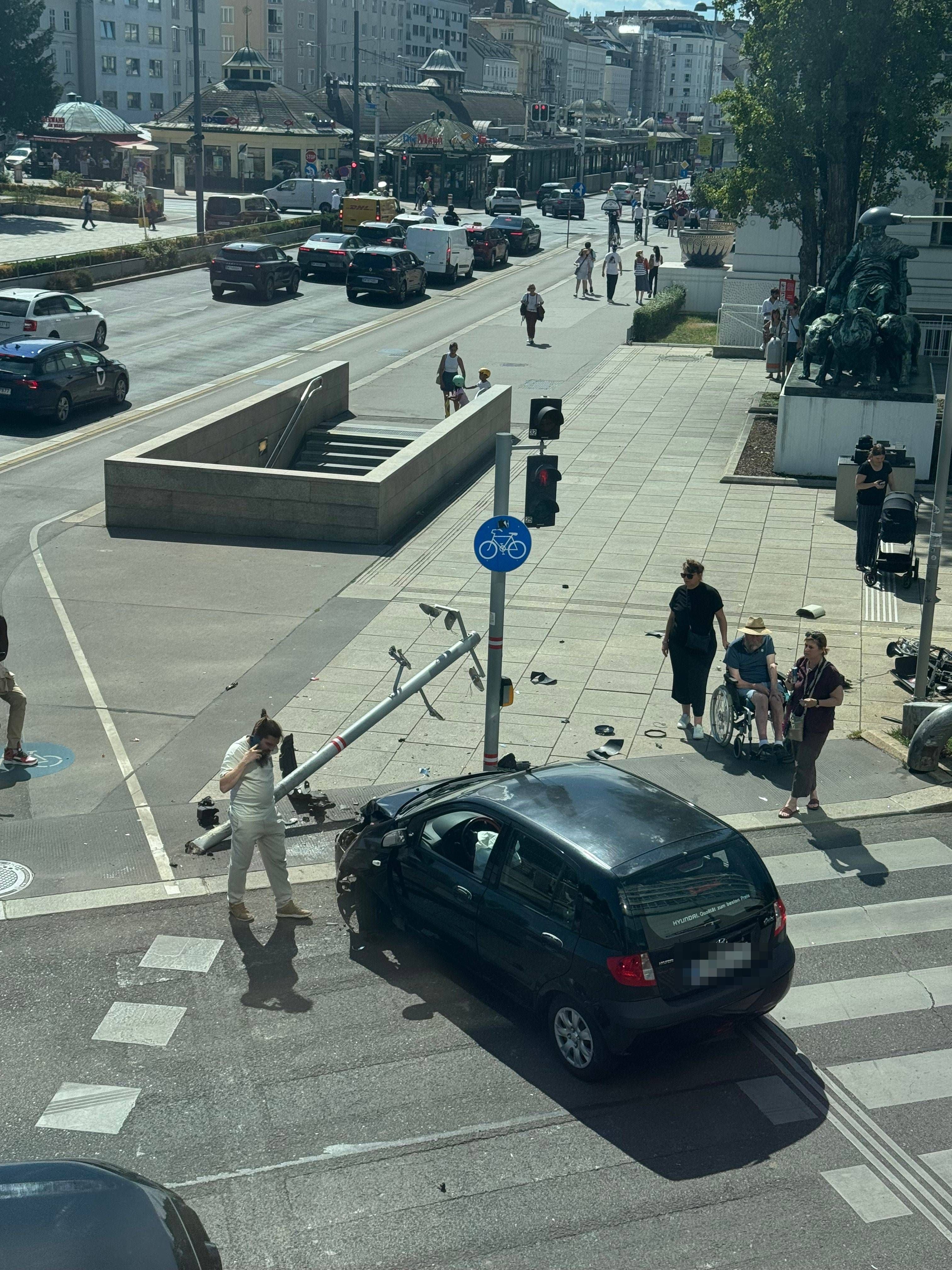 Ein schwarzes Auto ist gegen eine Ampel gefahren, die auf den Gehweg gefallen ist.