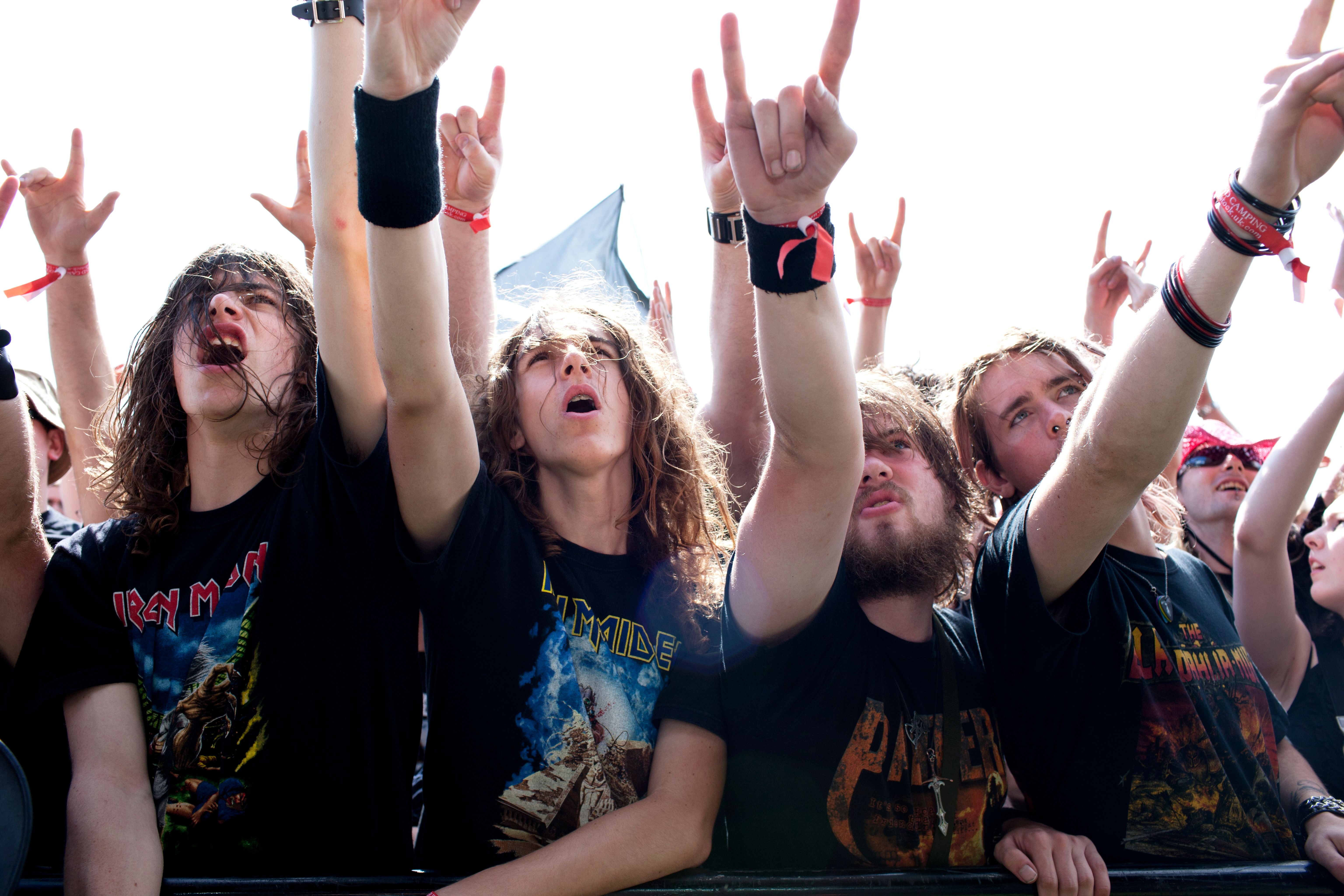 Junge Leute jubeln bei einem Open-Air-Konzert und zeigen die Metal-Handgeste.