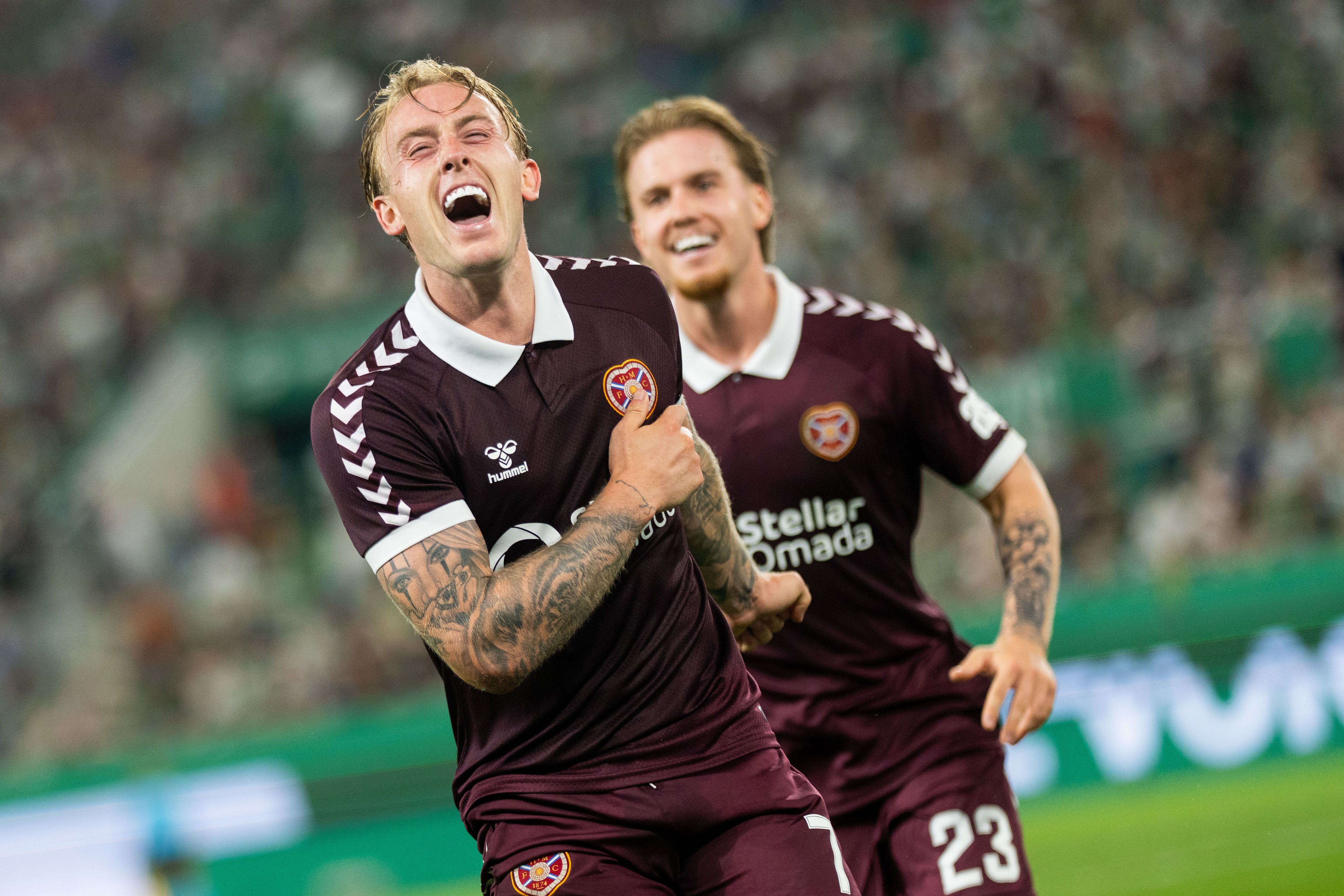 Ein Fußballspieler von Heart of Midlothian jubelt ausgelassen nach einem Tor, ein Mitspieler läuft hinterher.