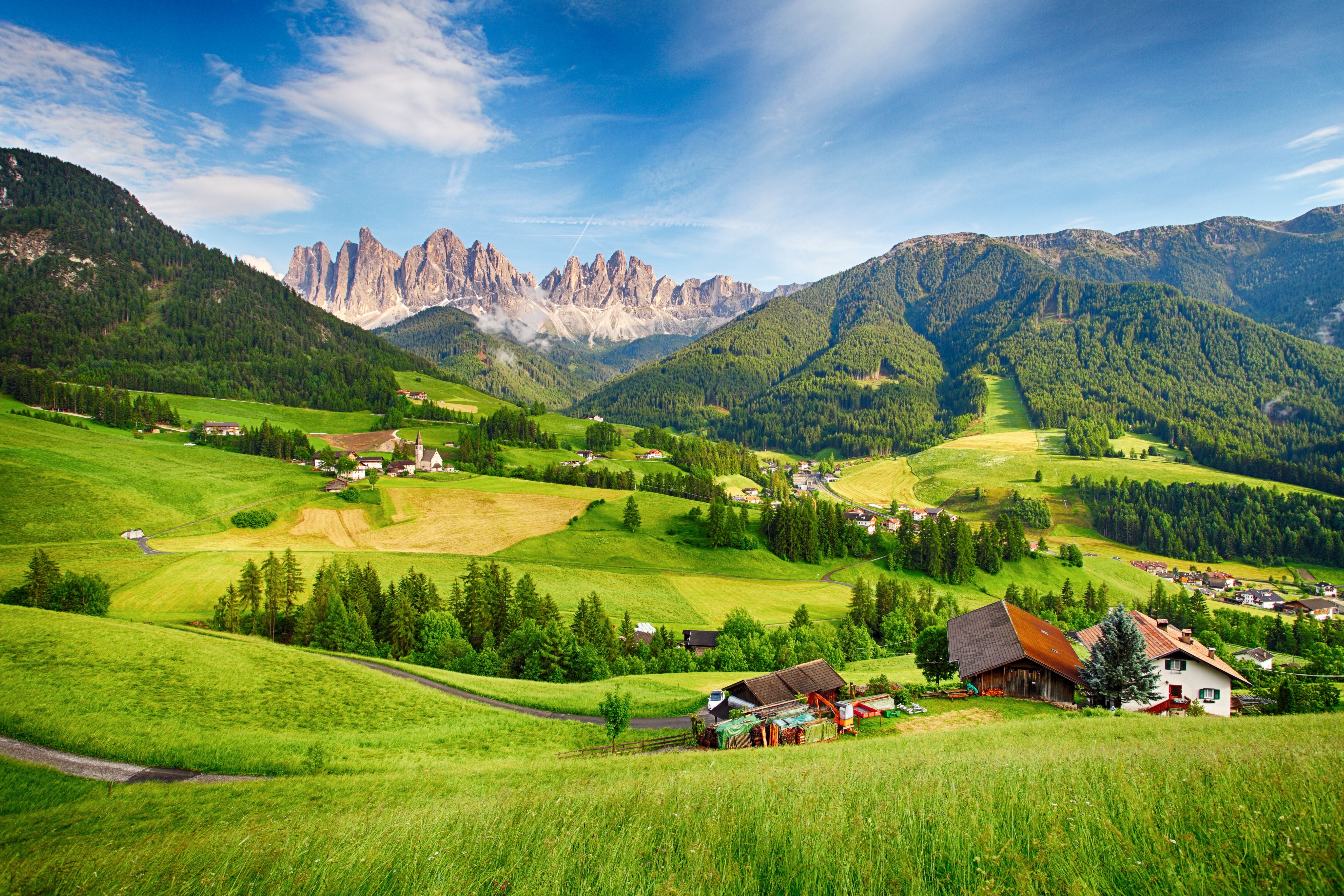 Grüne Täler, verstreute Häuser und Berge der Dolomiten im sonnigen Villnößtal.