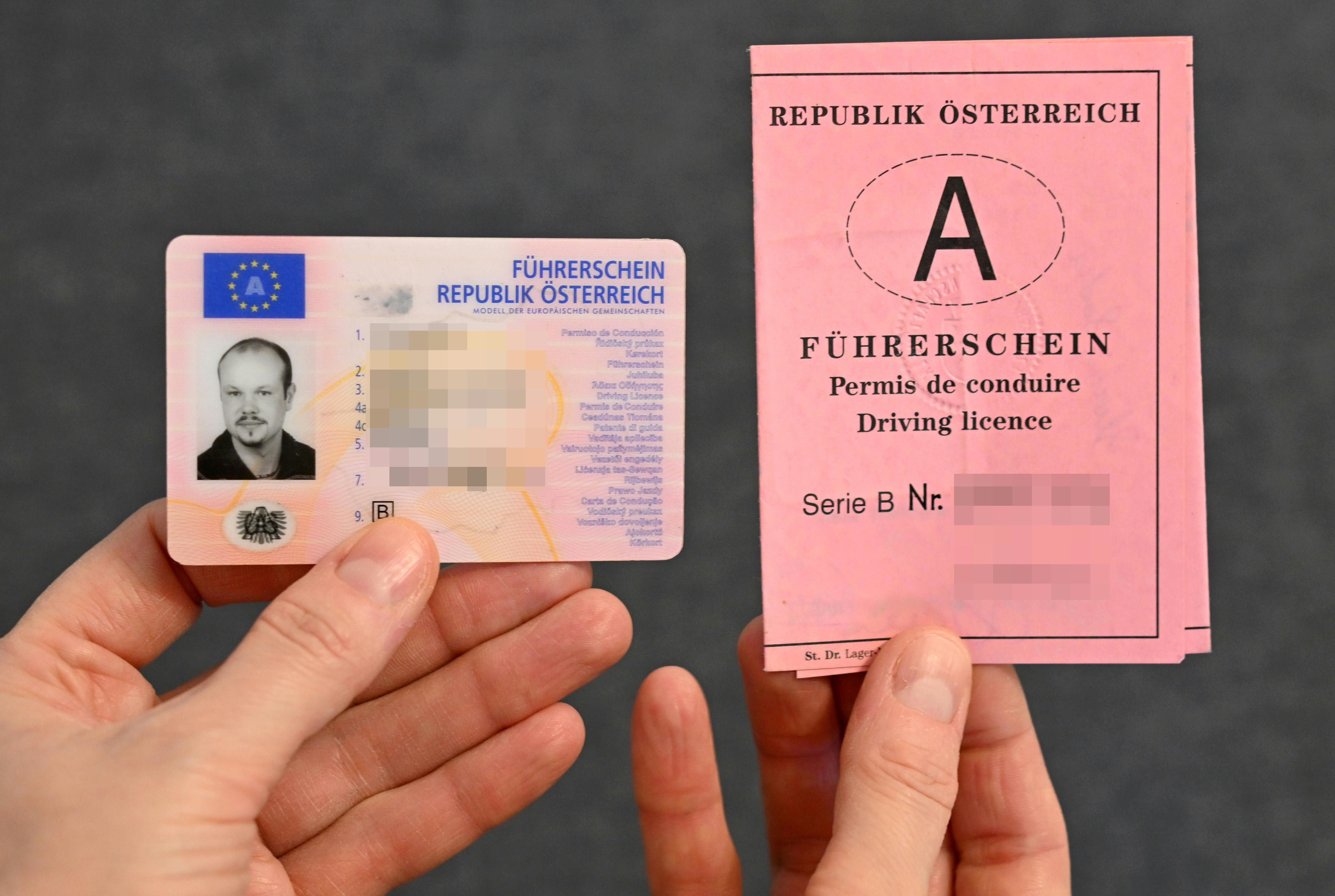 Zwei Hände halten einen österreichischen Scheckkartenführerschein und einen rosa Papierführerschein.