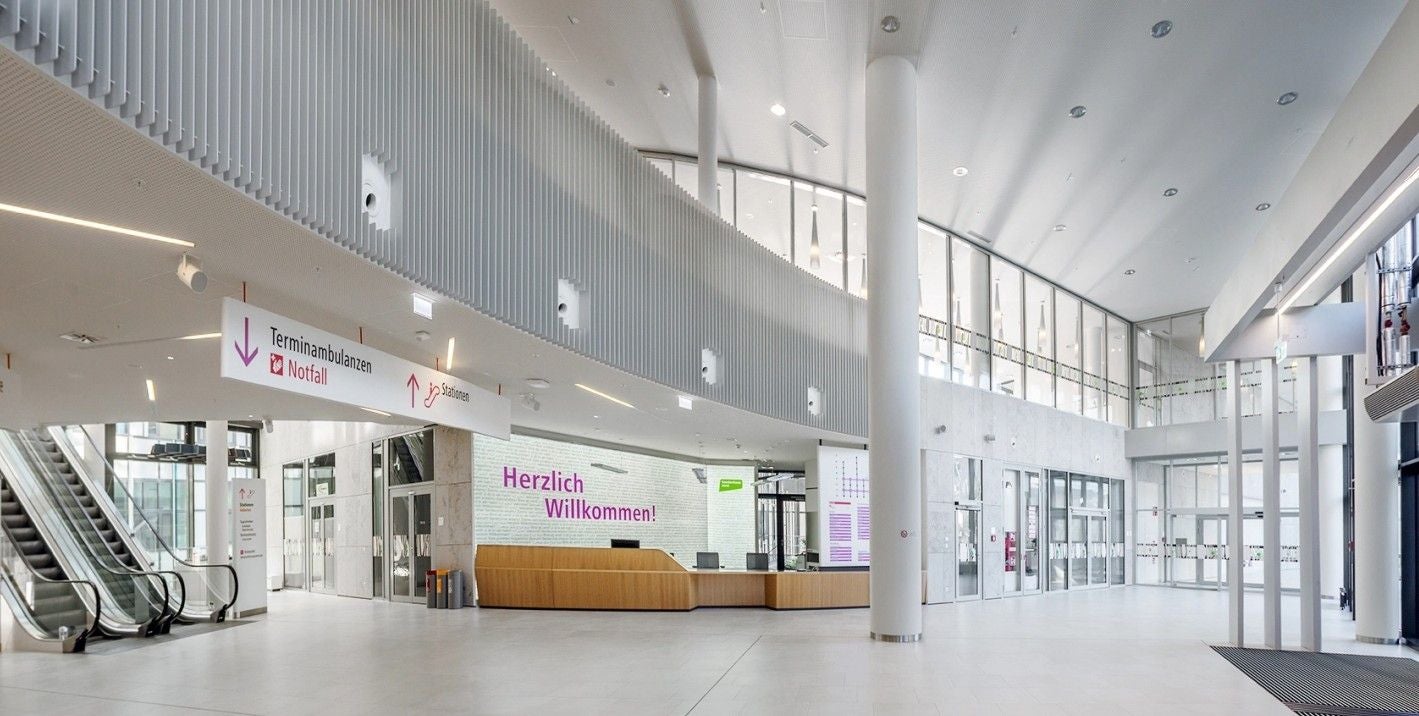 Heller Eingangsbereich der Klinik Floridsdorf mit Empfang, Rolltreppen und Willkommensschild.