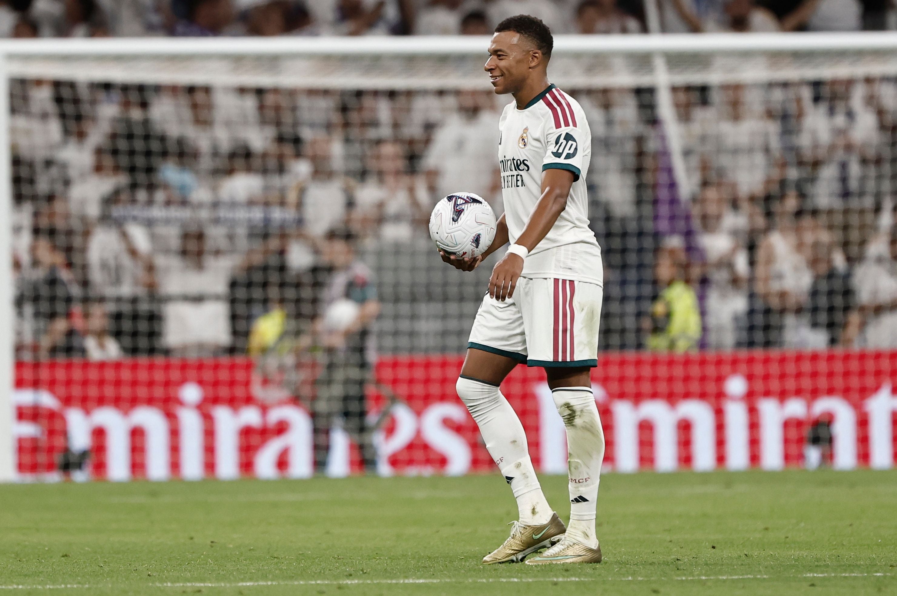 Kylian Mbappé jubelt im Real-Madrid-Trikot mit Ball nach einem Spiel im Stadion.
