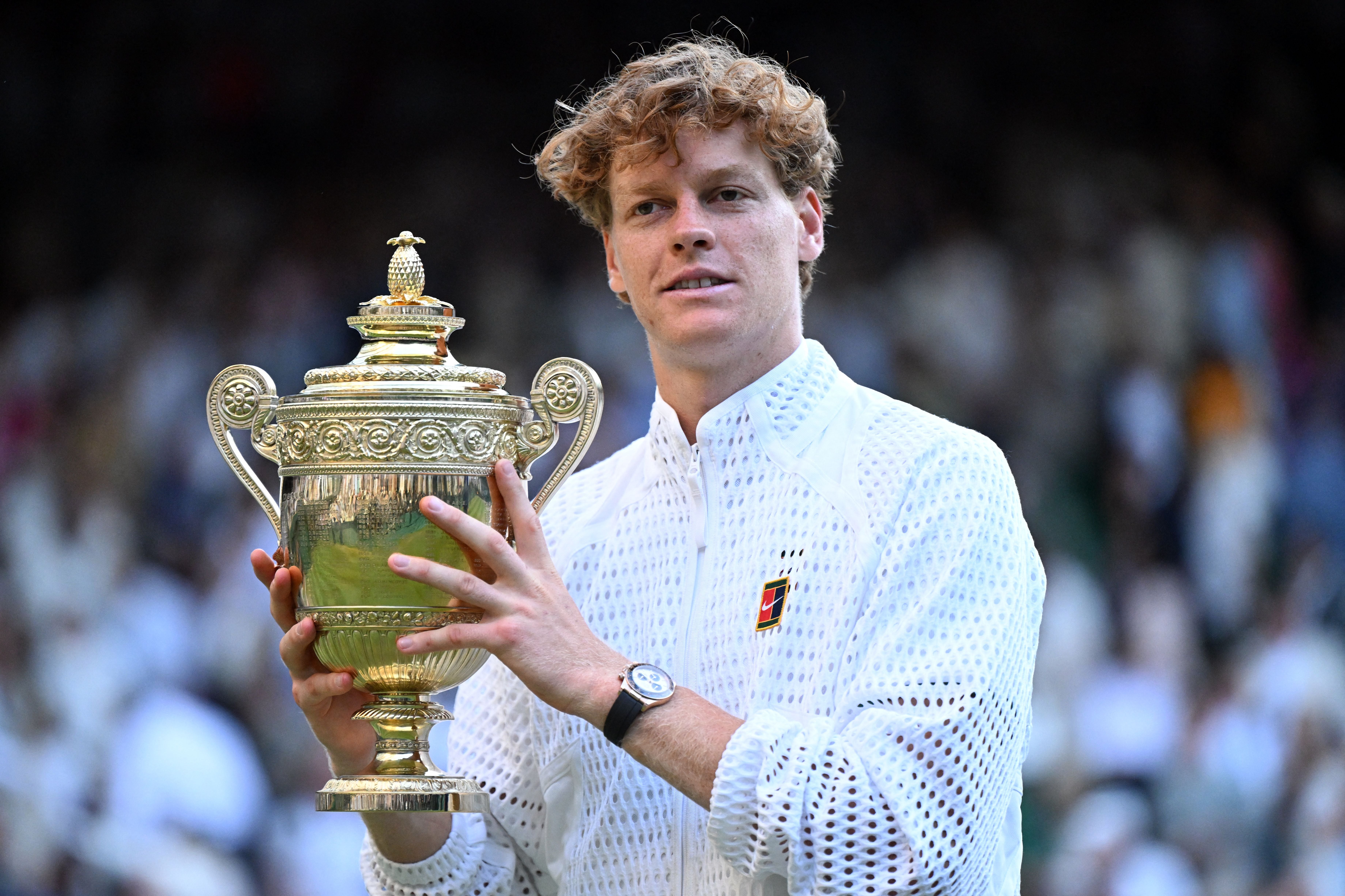 Ein Tennisspieler hält nach einem Sieg einen großen goldenen Pokal in den Händen.