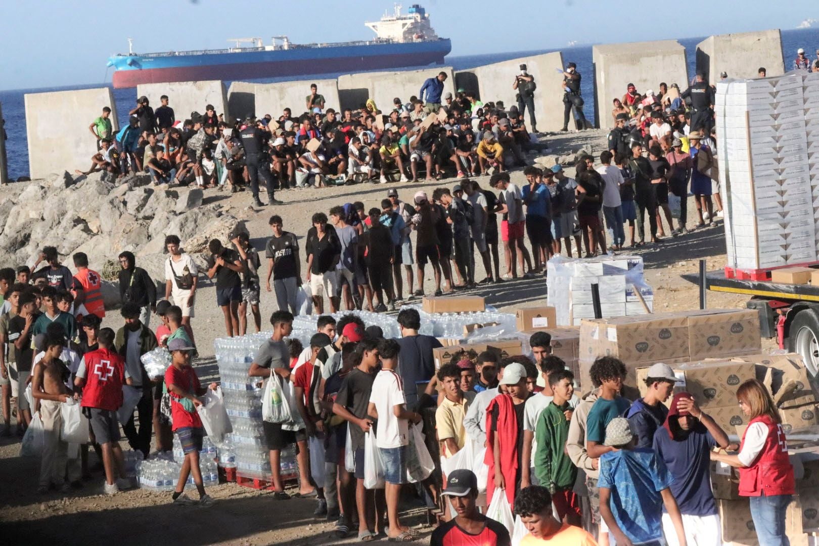 Menschen stehen an, um bei einer Essensausgabe des Roten Kreuzes in Ceuta Lebensmittel zu erhalten.