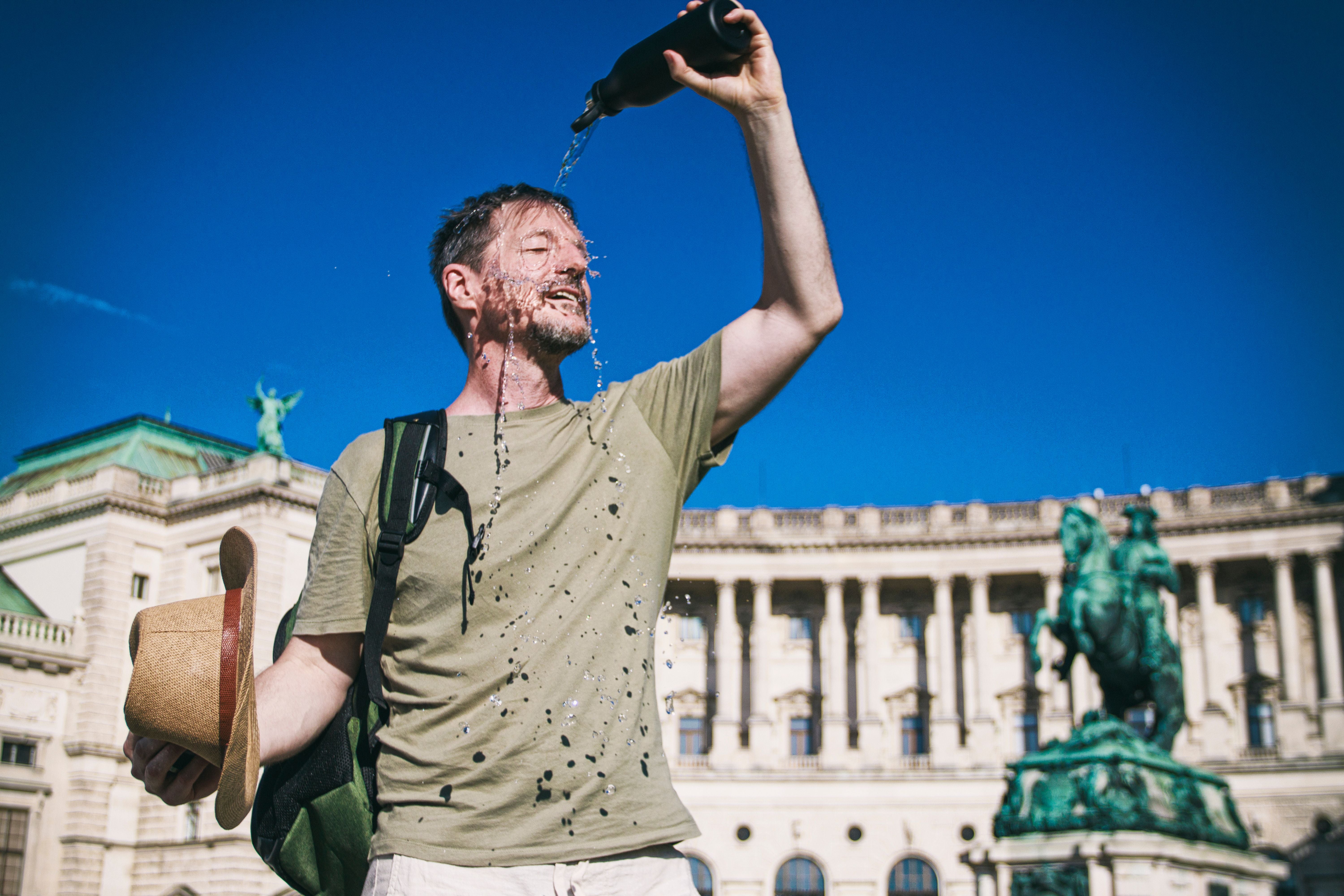 Tourist in Wien kühlt sich bei Hitze mit Wasser aus einer Flasche ab.