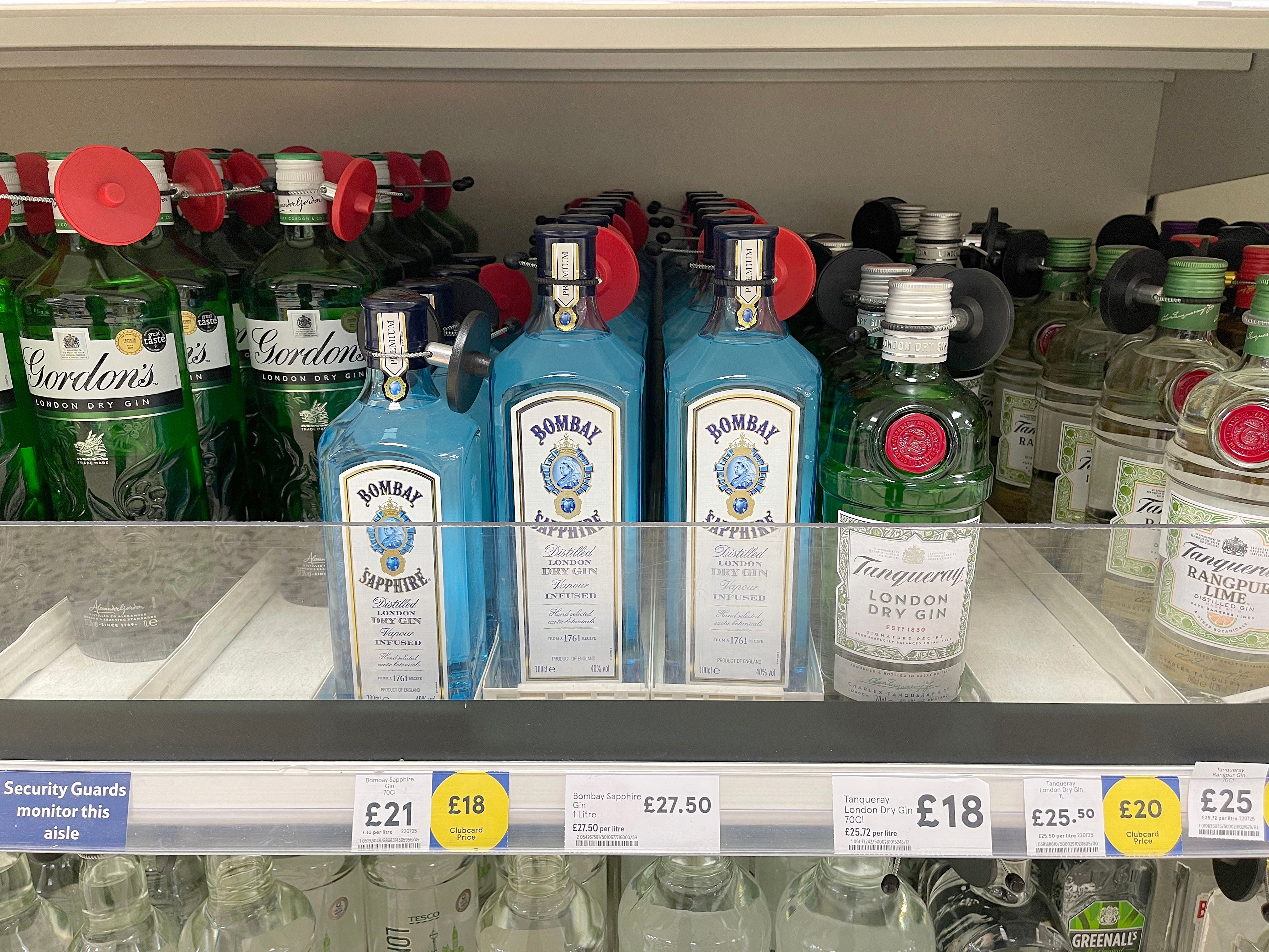 Gin-Flaschen verschiedener Marken mit Diebstahlsicherungen in einem Supermarktregal.