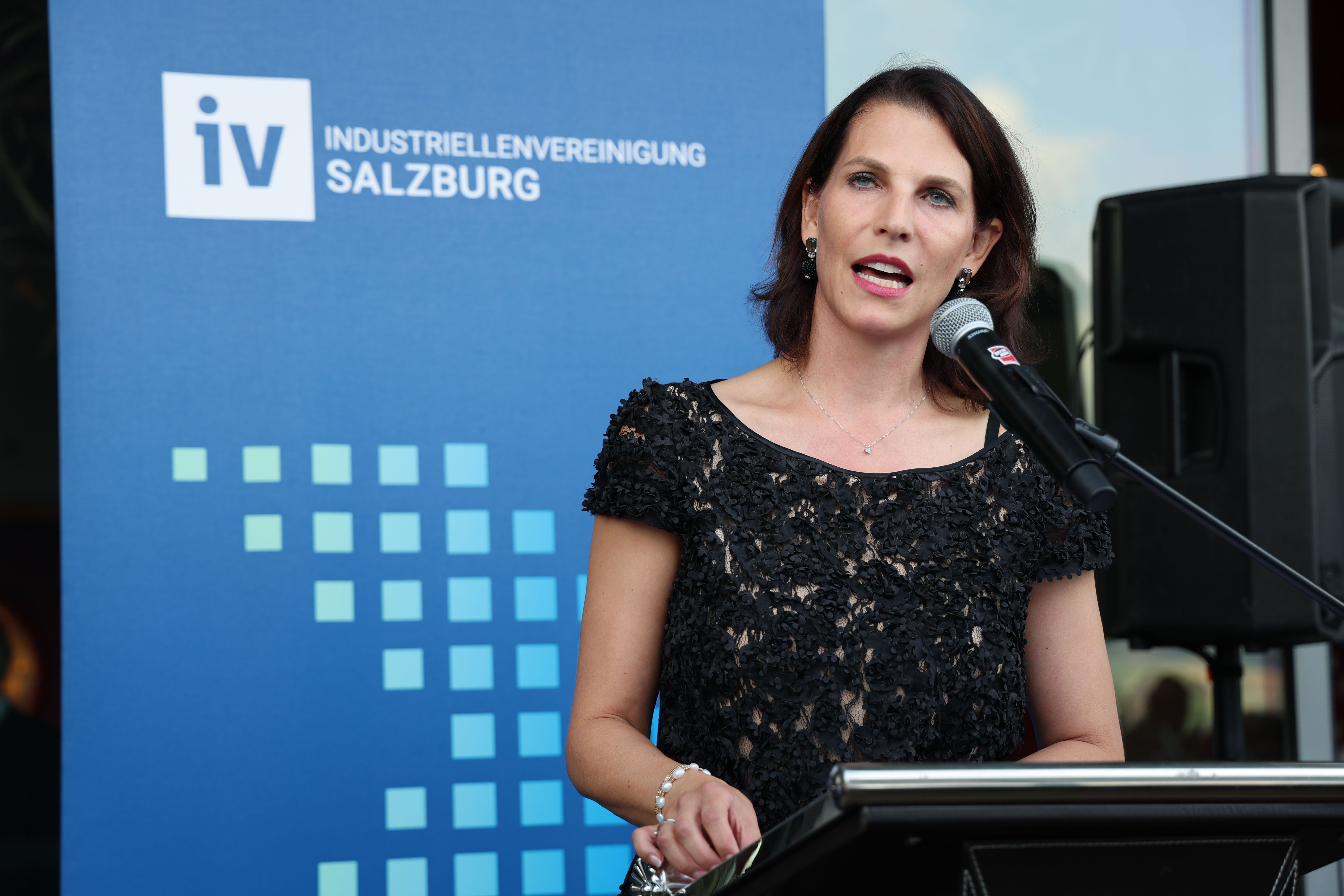 Frau hält eine Rede am Mikrofon bei einer Veranstaltung der Industriellenvereinigung Salzburg.