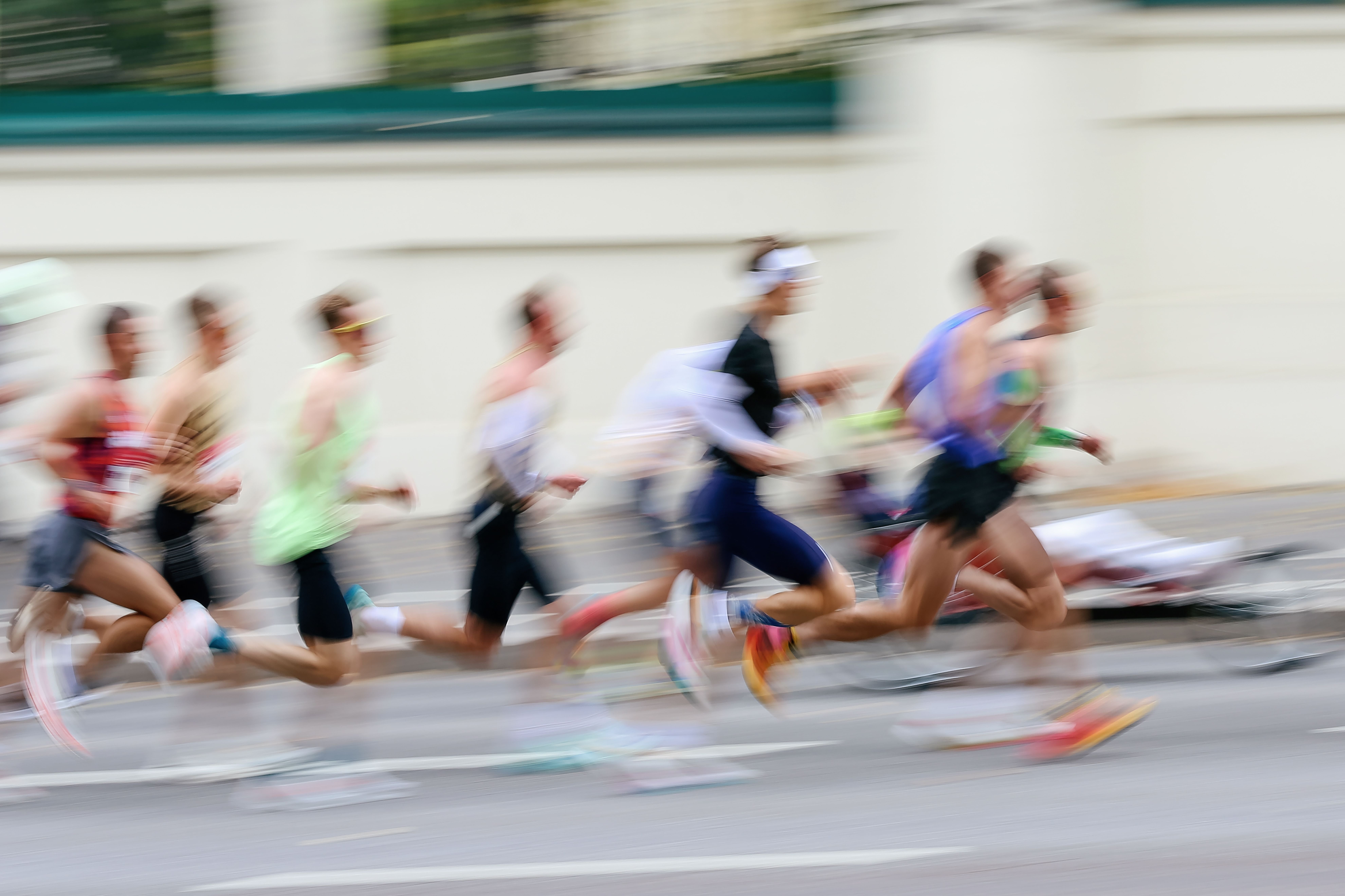 Verschwommene Silhouetten mehrerer Menschen laufen bei einem Marathon auf der Straße.