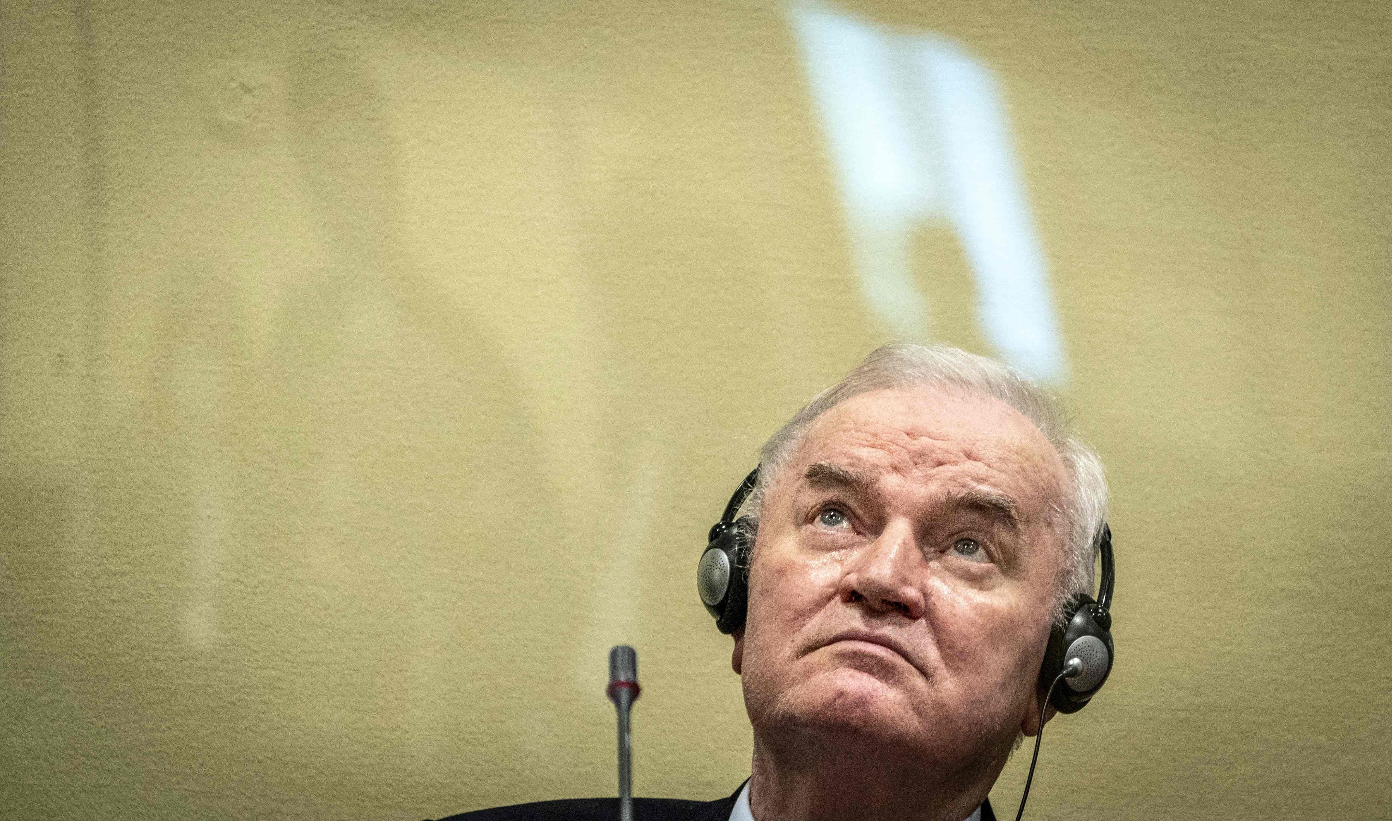 Ein älterer Mann mit Kopfhörern sitzt vor einem Mikrofon und blickt nach oben.