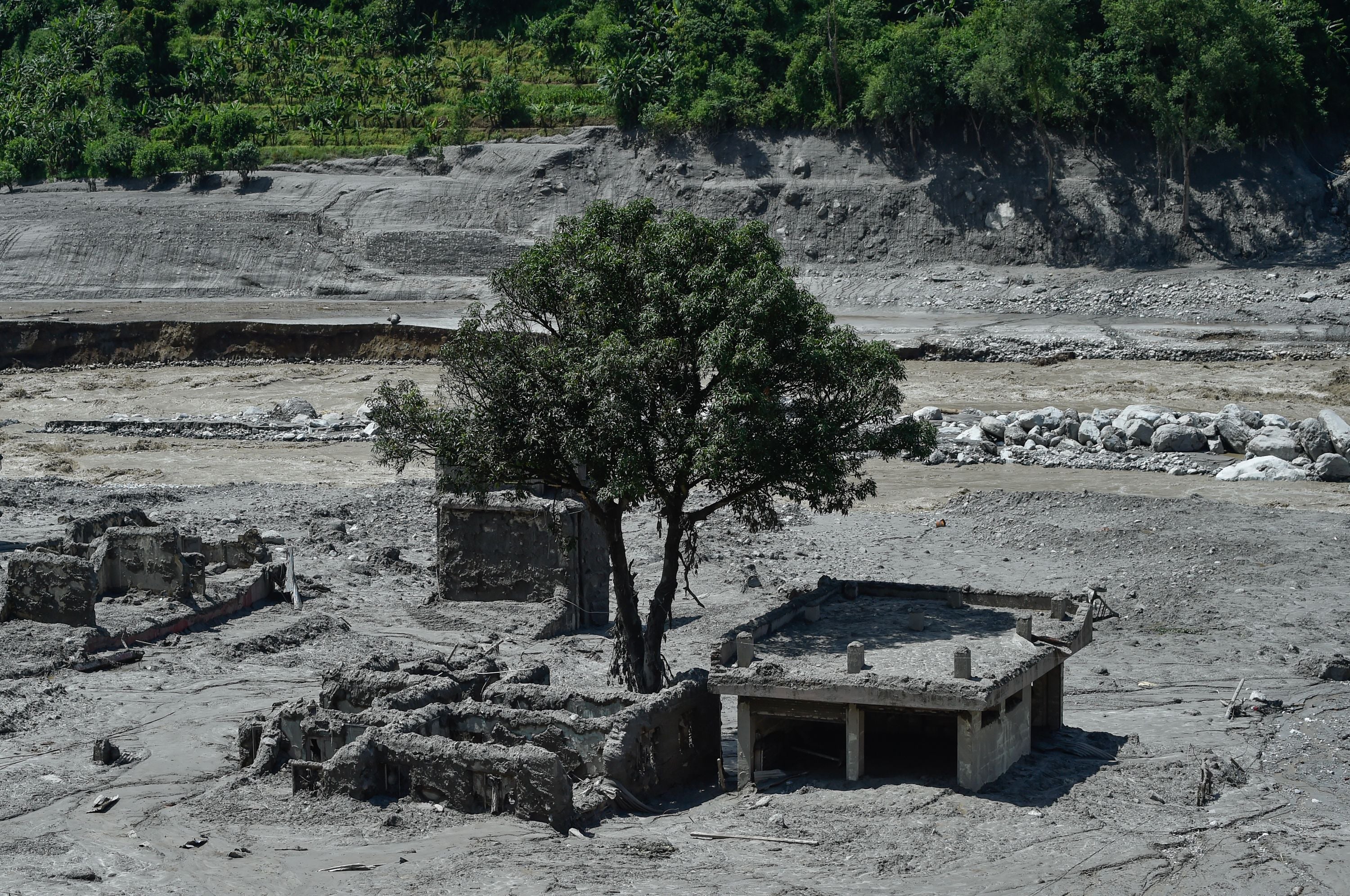 Ein teilweise im Schlamm versunkenes Haus nach einer Überschwemmung in Trishuli, Nepal, mit Baum.