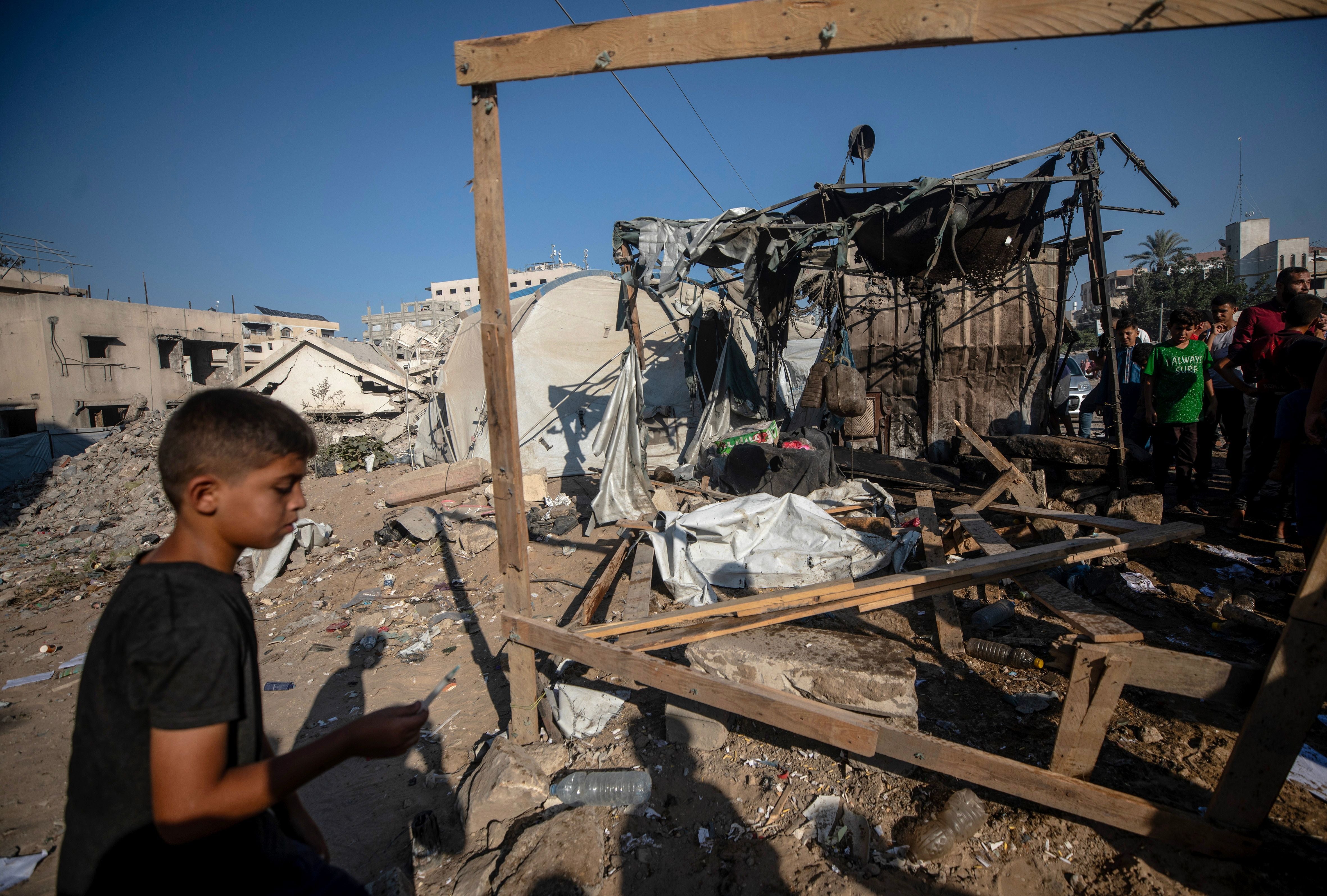 Zerstörte Gebäude in Gaza mit umstehenden Menschen und Trümmern nach einem Luftangriff.