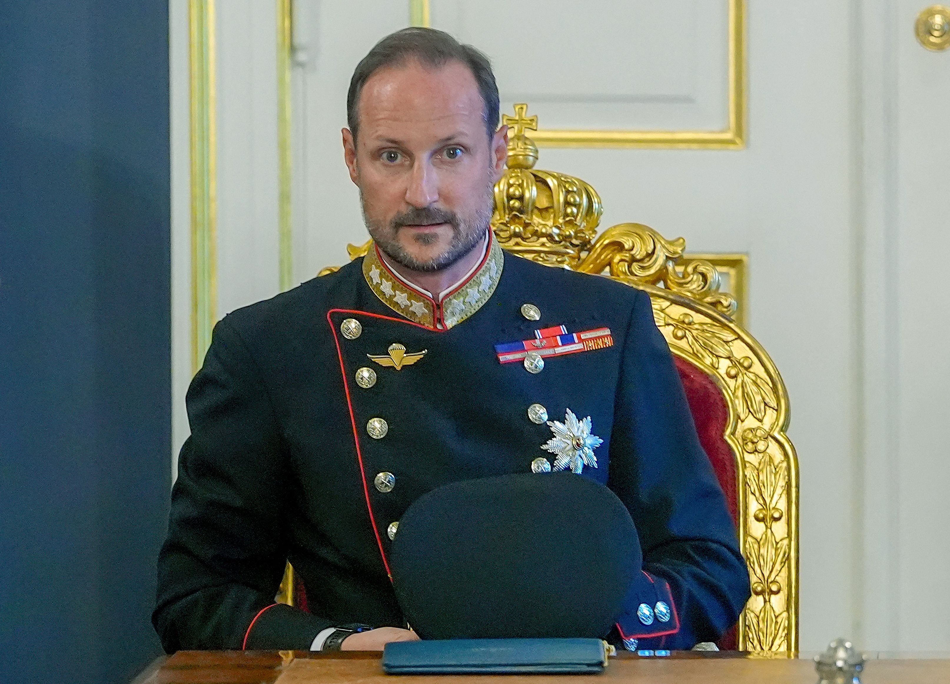 Ein Mann in Uniform sitzt auf einem goldenen Thronstuhl in einem prunkvollen Raum.