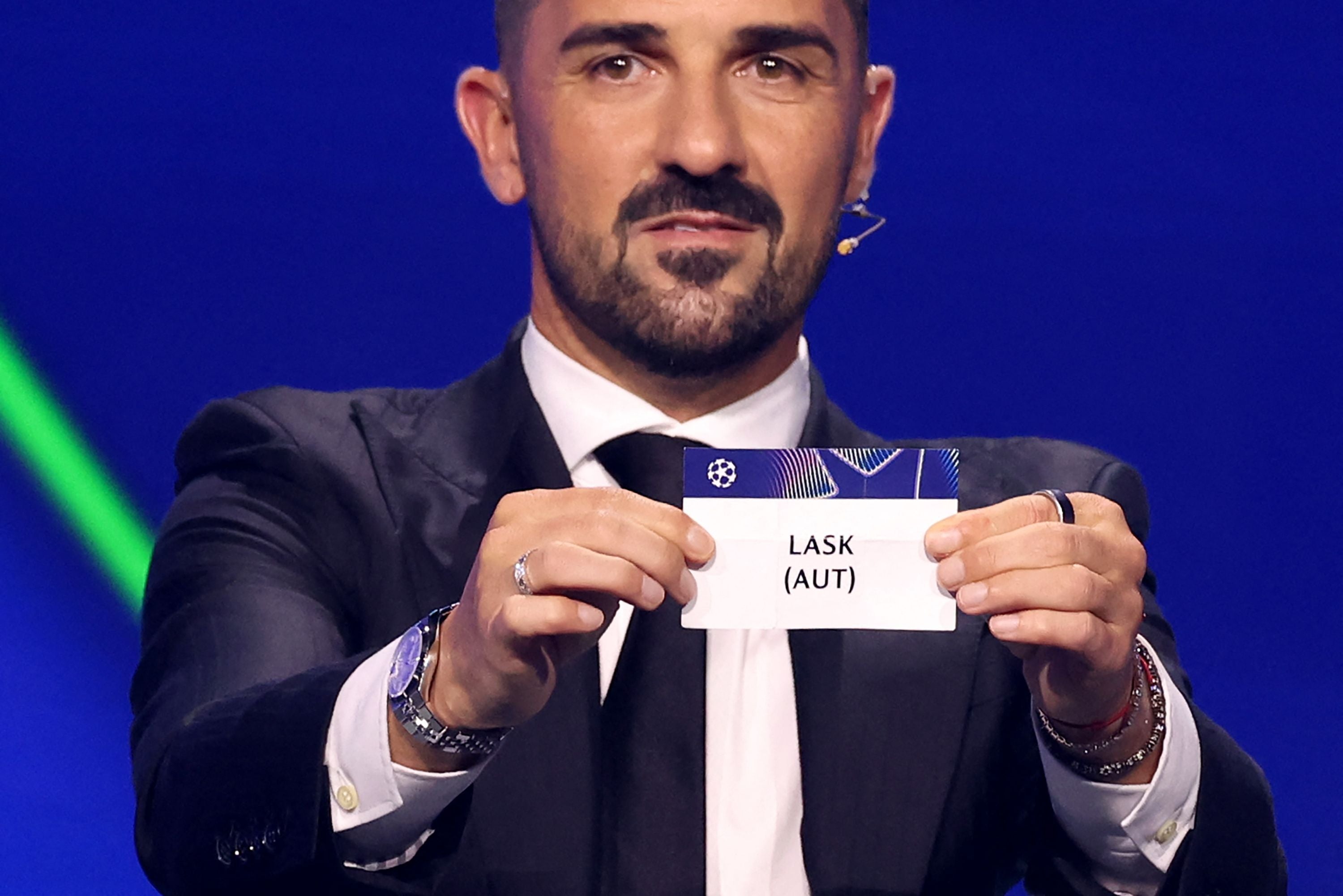 Ein Mann im Anzug hält bei einer Auslosung einen Zettel mit der Aufschrift "LASK (AUT)".