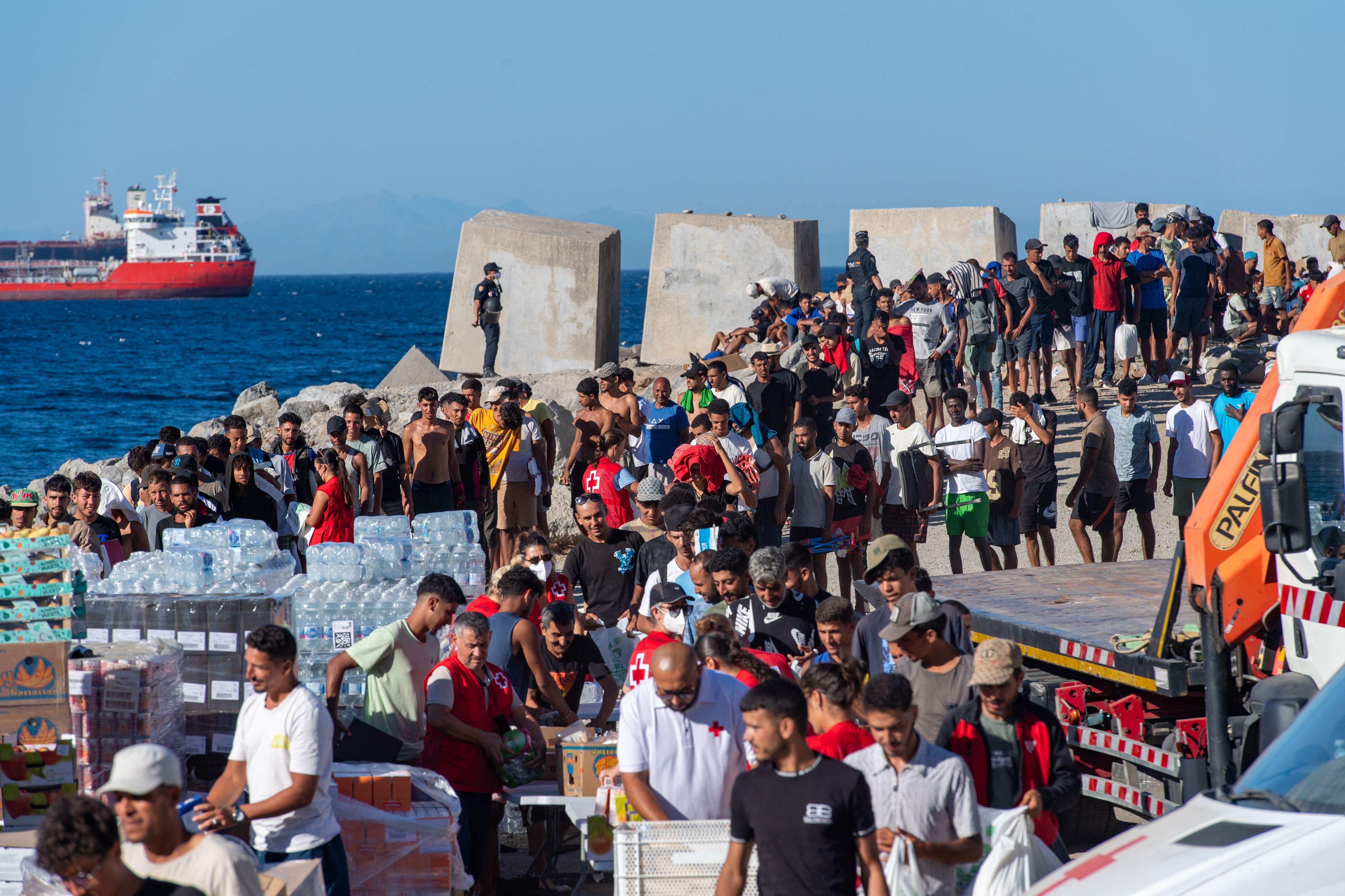 Migranten stehen am 28. August am Strand El Trampolin in Ceuta für eine Essensausgabe des Roten Kreuzes an.