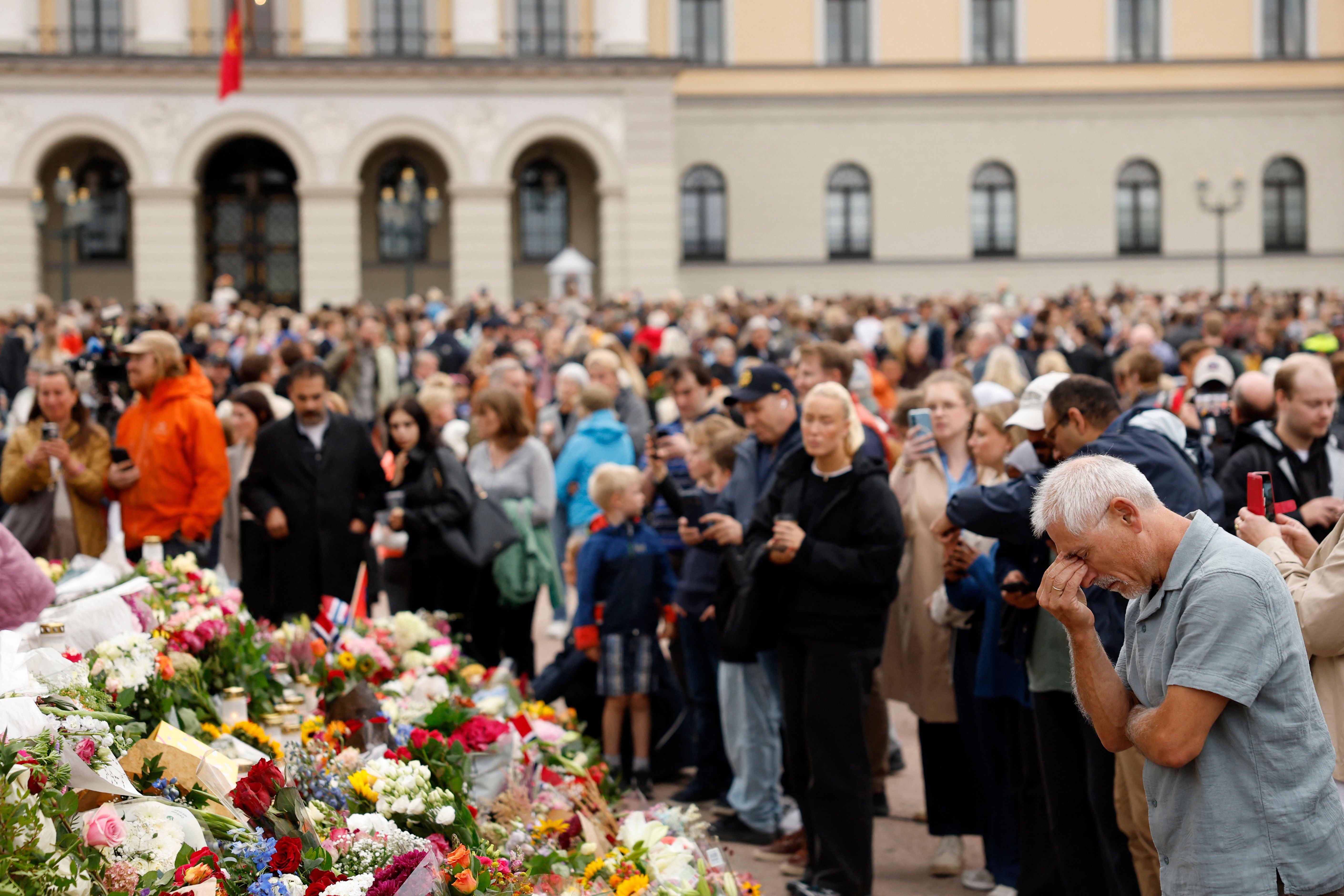 Viele Menschen trauern an einem Blumendenkmal vor dem königlichen Palast in Oslo.