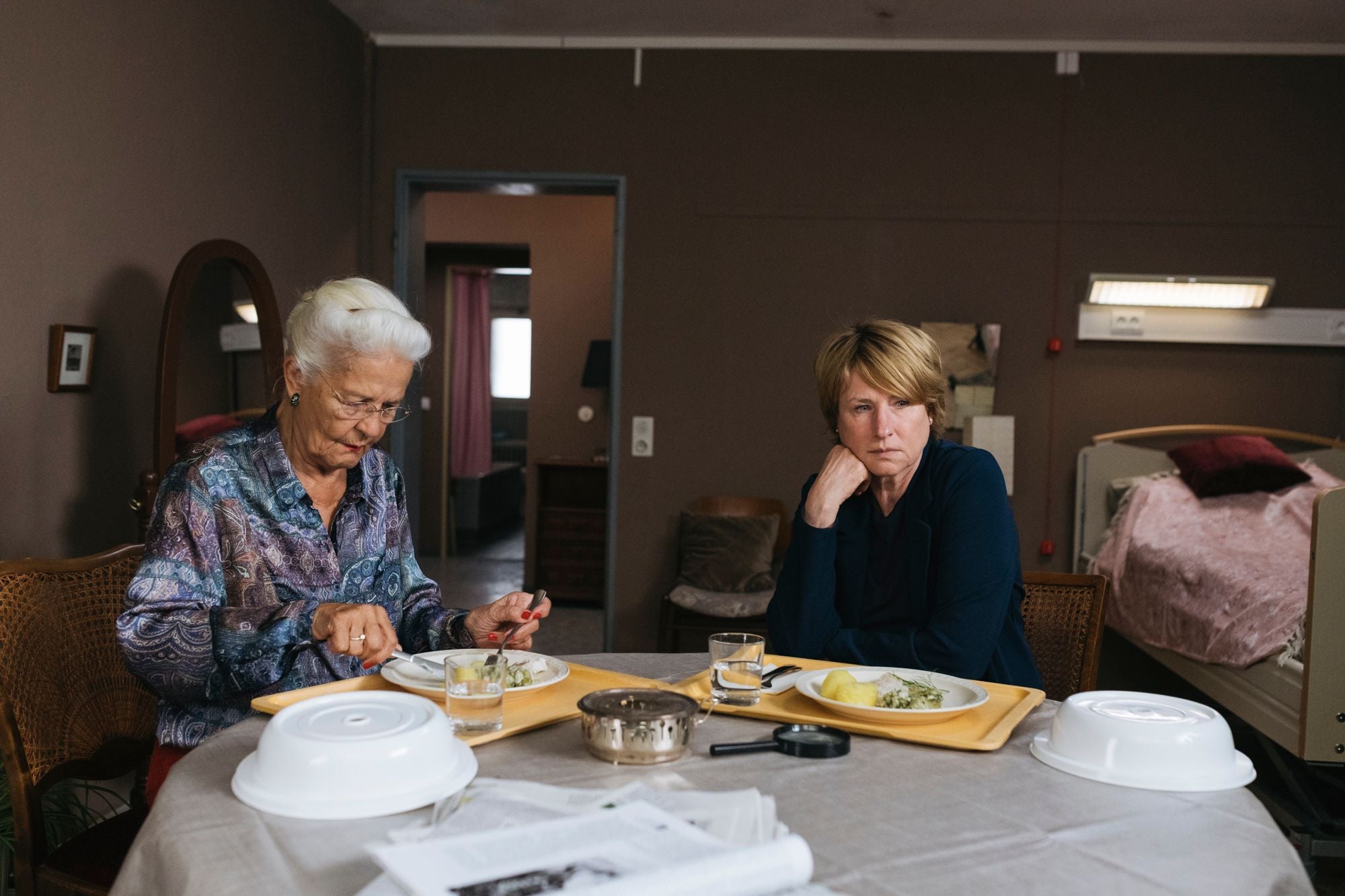 Zwei Frauen sitzen an einem Tisch im Pflegezimmer und essen gemeinsam eine Mahlzeit.