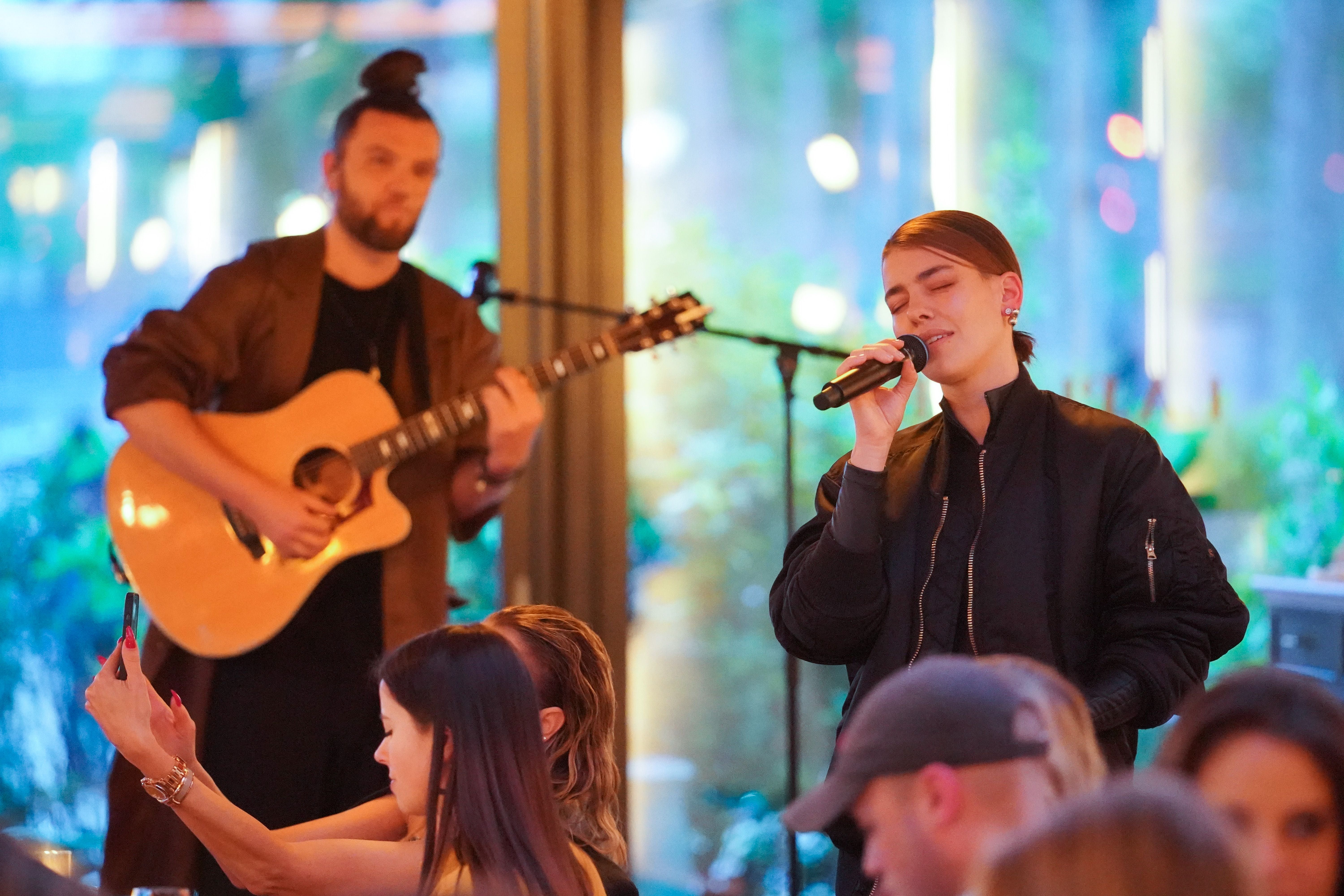 Zwei Musiker treten mit Gitarre und Mikrofon bei einer Indoor-Veranstaltung auf.