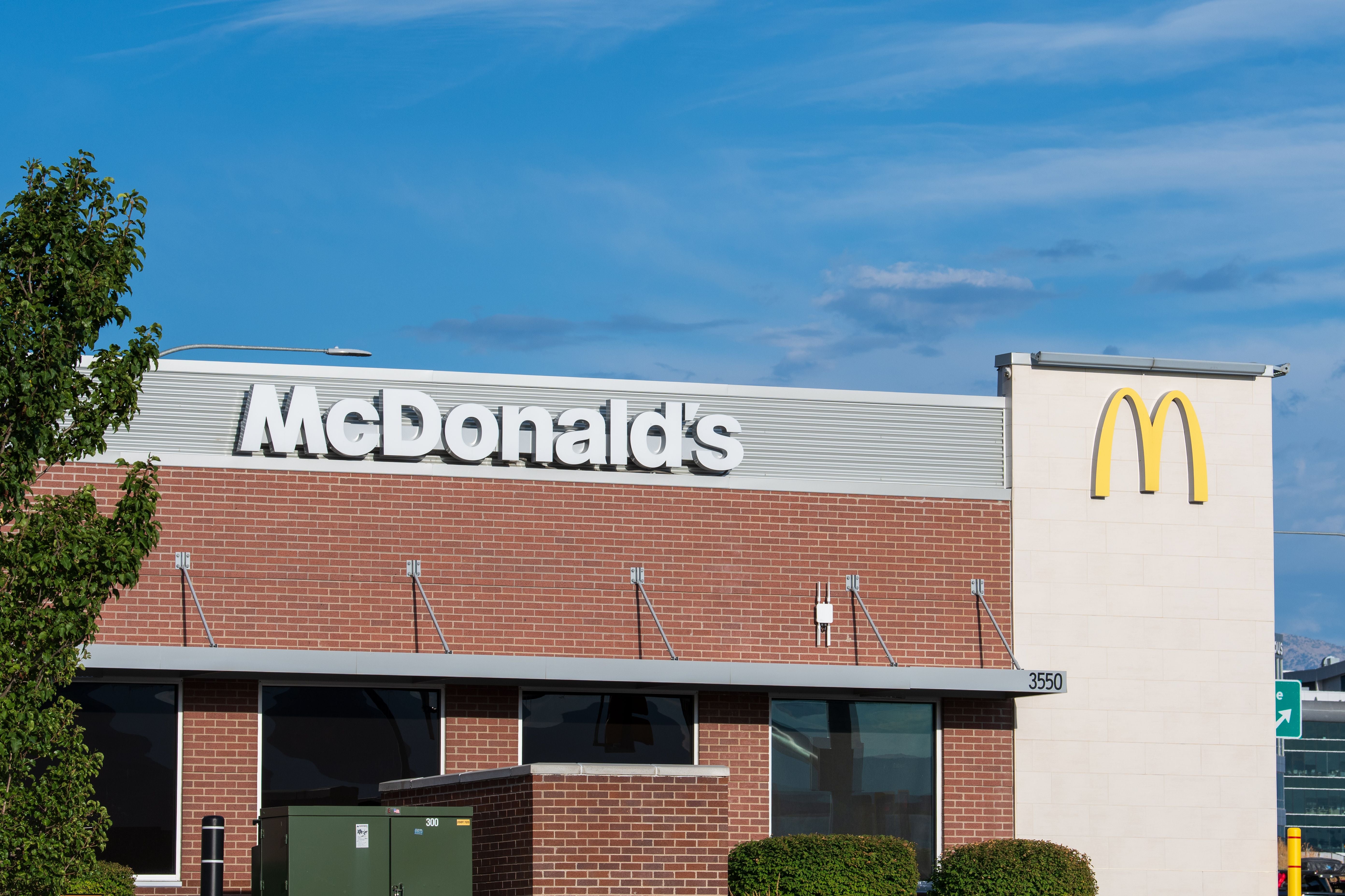 McDonald's Restaurant mit goldenem Logo und roter Backsteinfassade bei blauem Himmel.