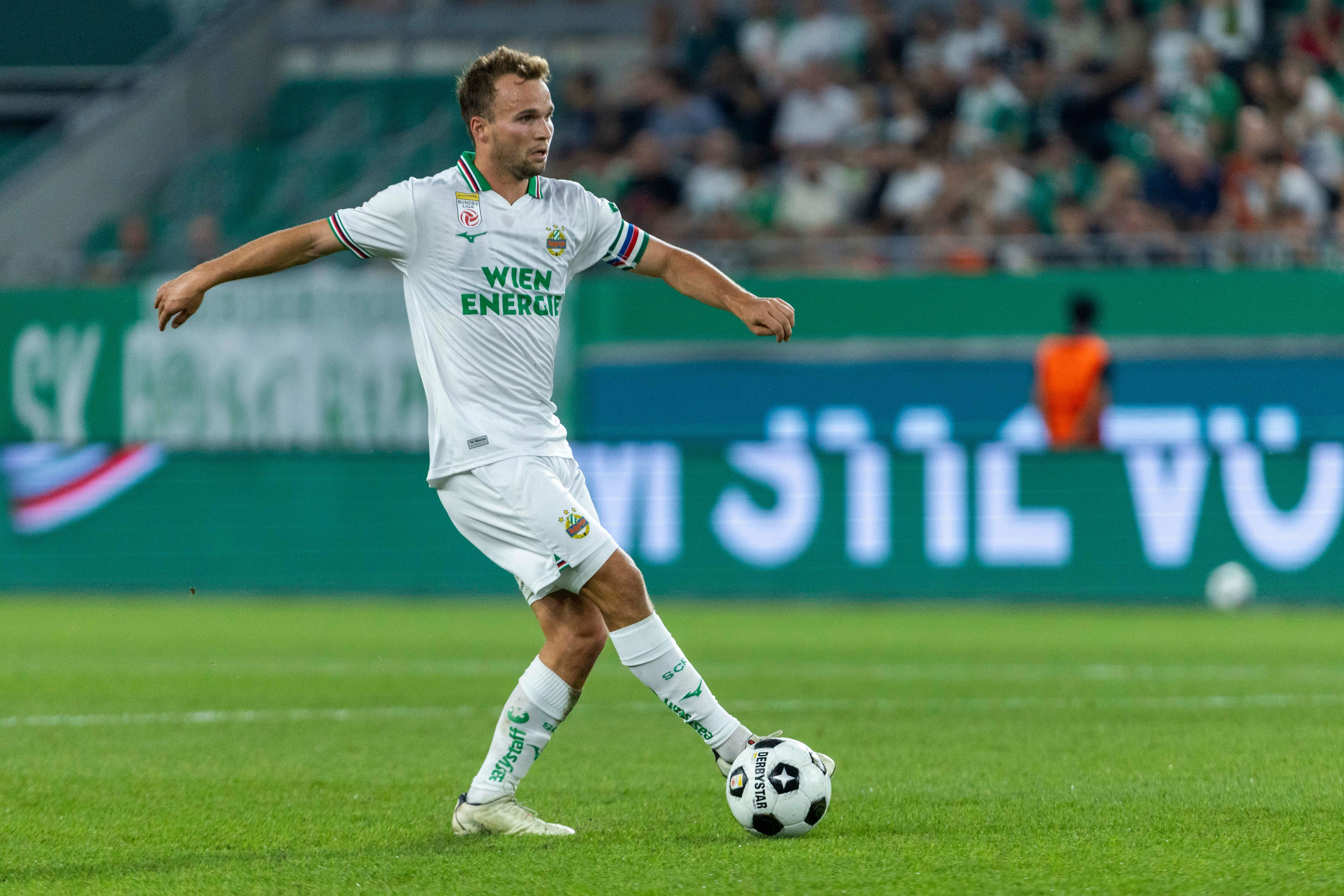 Ein Fußballspieler von Rapid Wien spielt den Ball im Stadion während eines Spiels.