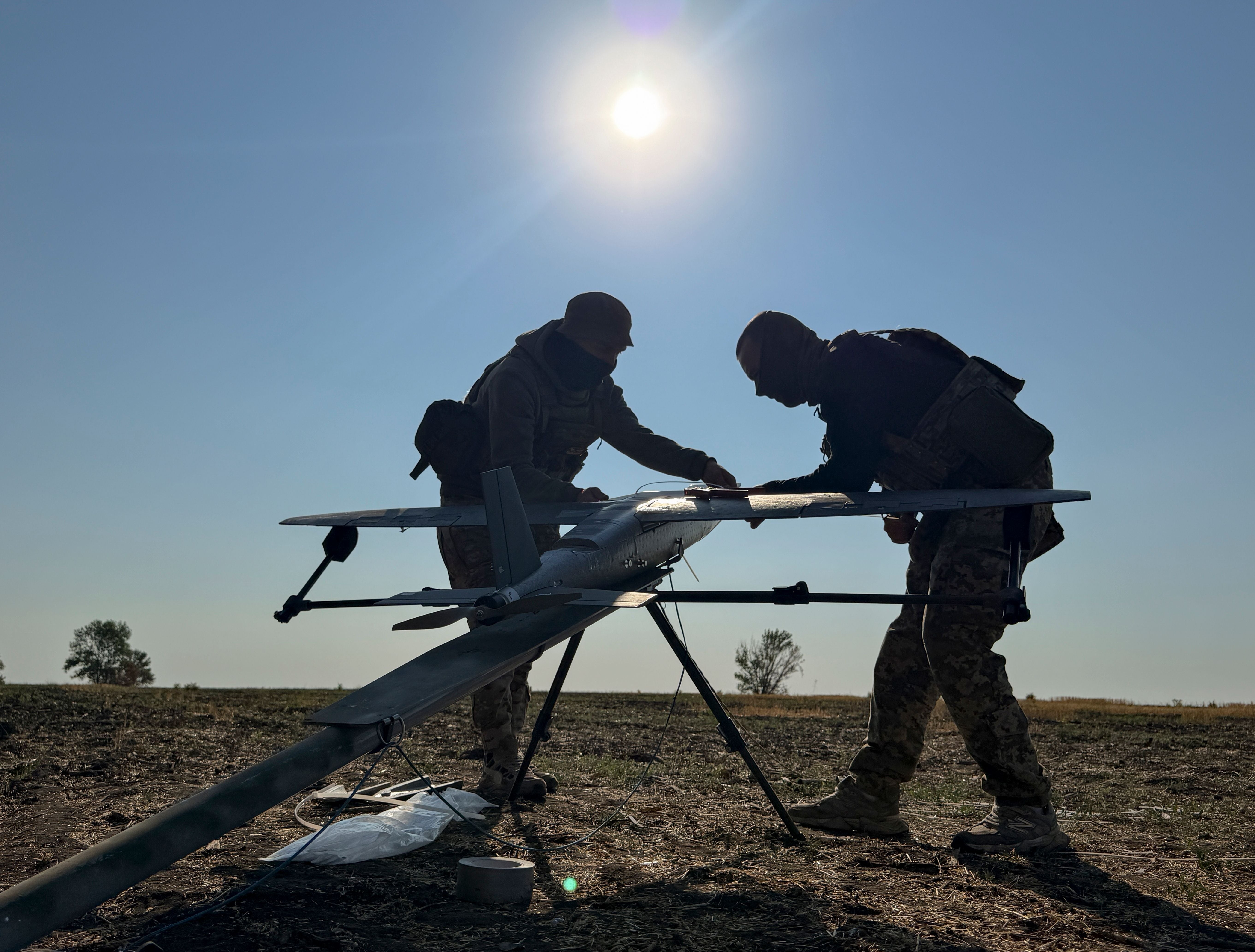 Zwei Soldaten bereiten eine Drohne auf einem Feld zum Start vor.