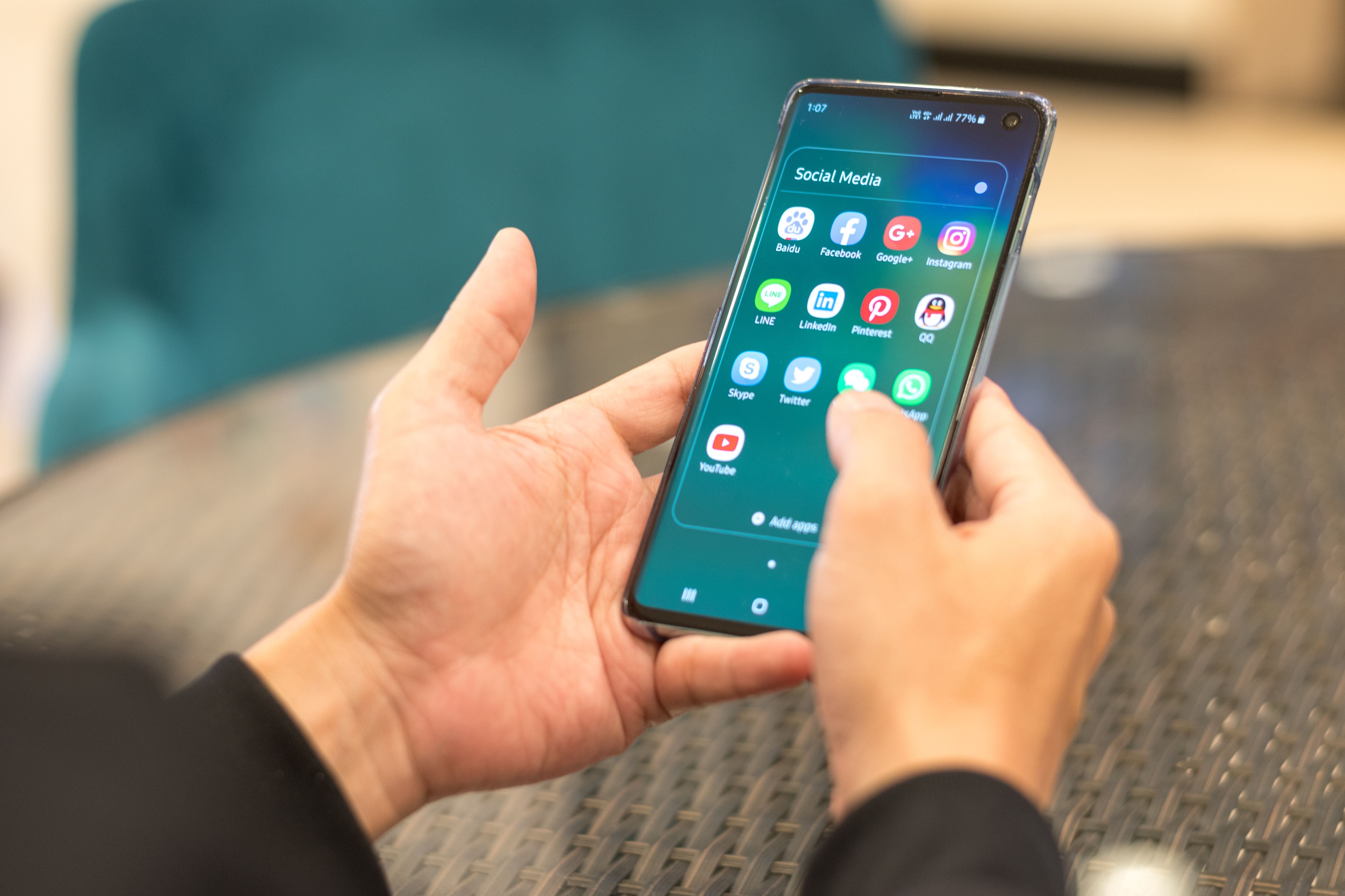 Eine Person hält ein Smartphone, das Social-Media-Apps auf dem Bildschirm zeigt.