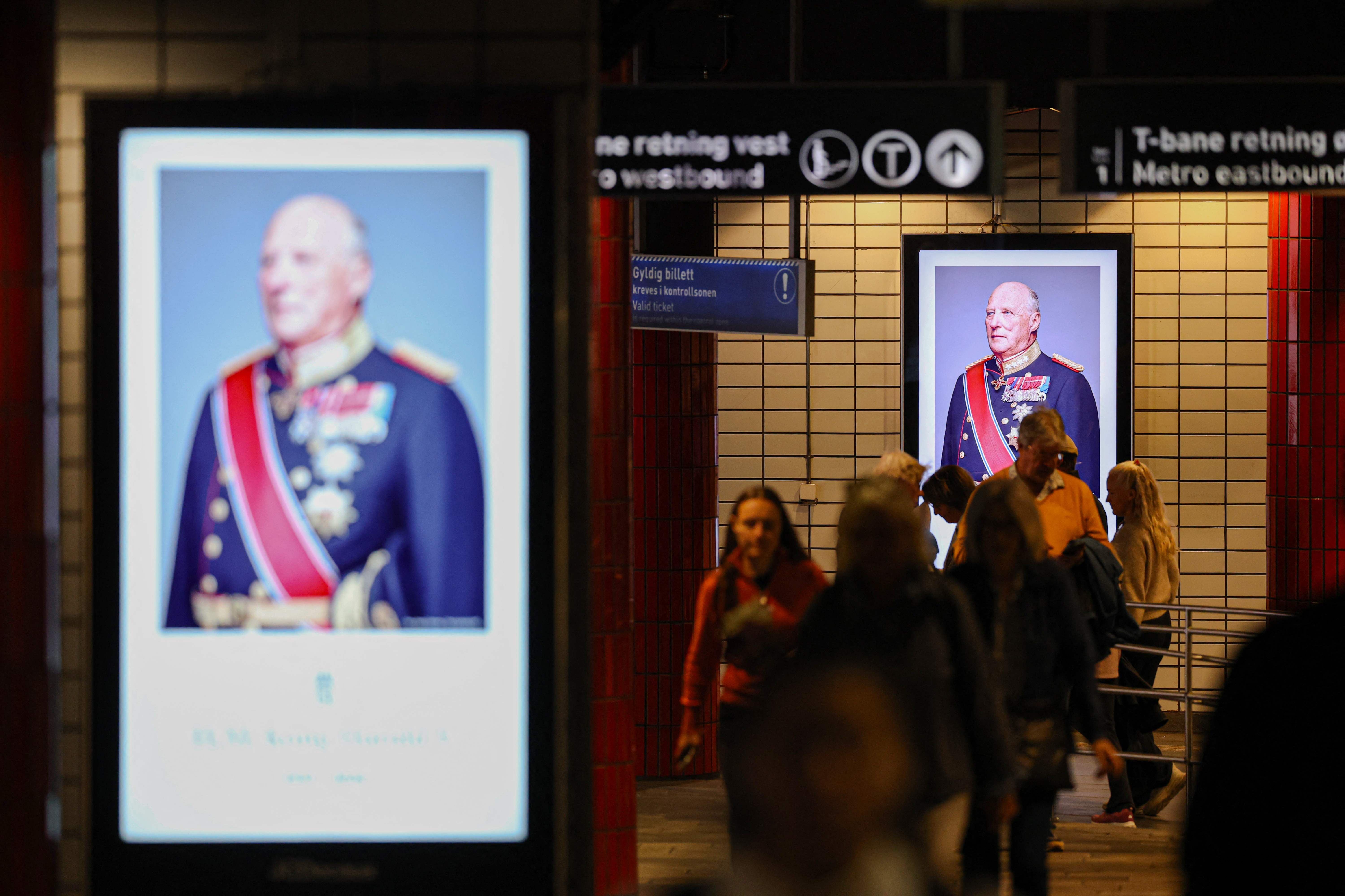 Menschen gehen durch eine U-Bahn-Station mit Porträts eines älteren Mannes in Uniform an den Wänden.