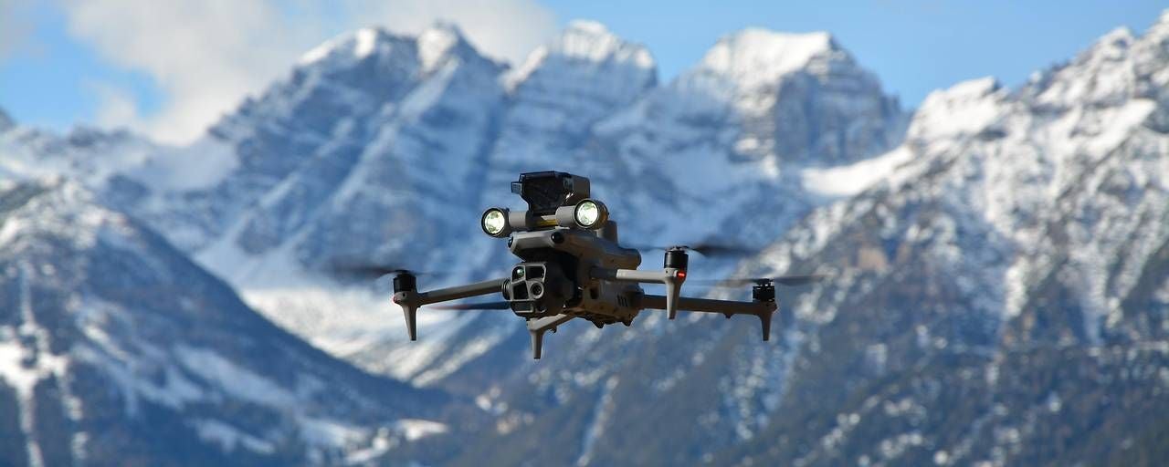 Eine Drohne fliegt vor schneebedeckten Bergen in einem Nationalpark.