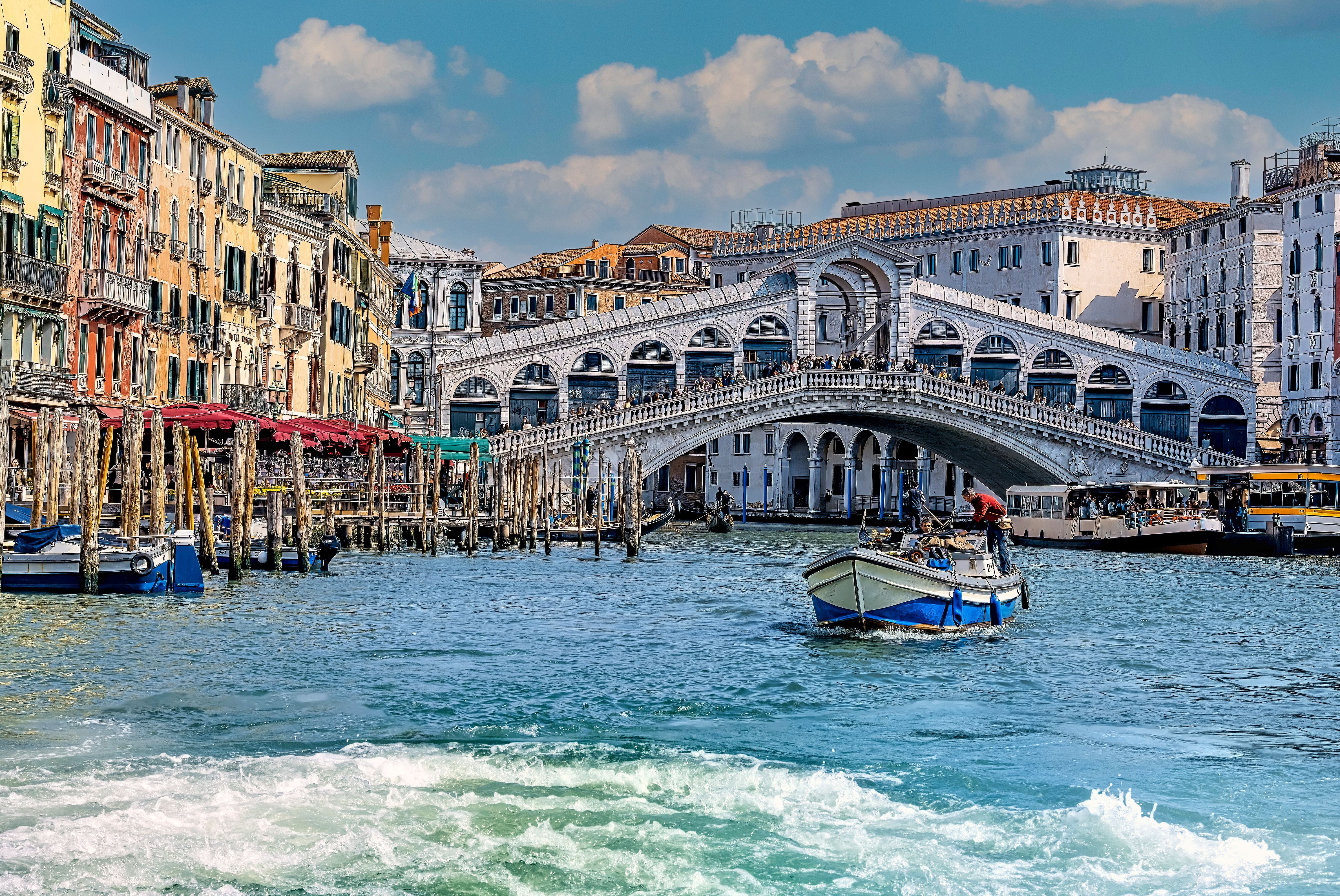 Blick auf die Rialtobrücke über dem Canal Grande in Venedig mit Booten und alten Häusern.