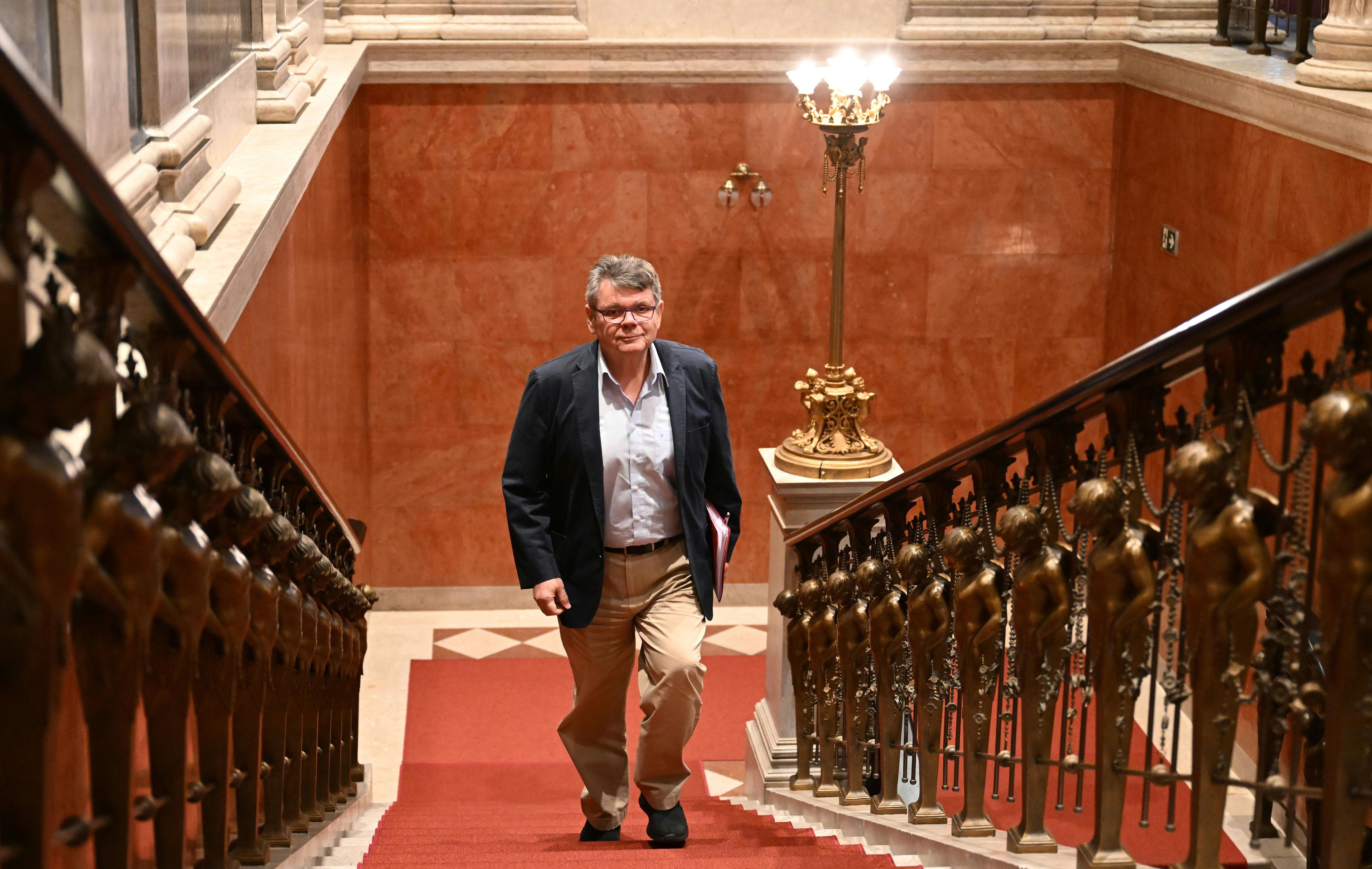 Ein Mann geht eine prunkvolle Treppe mit rotem Teppich und verzierten Geländern hinauf.