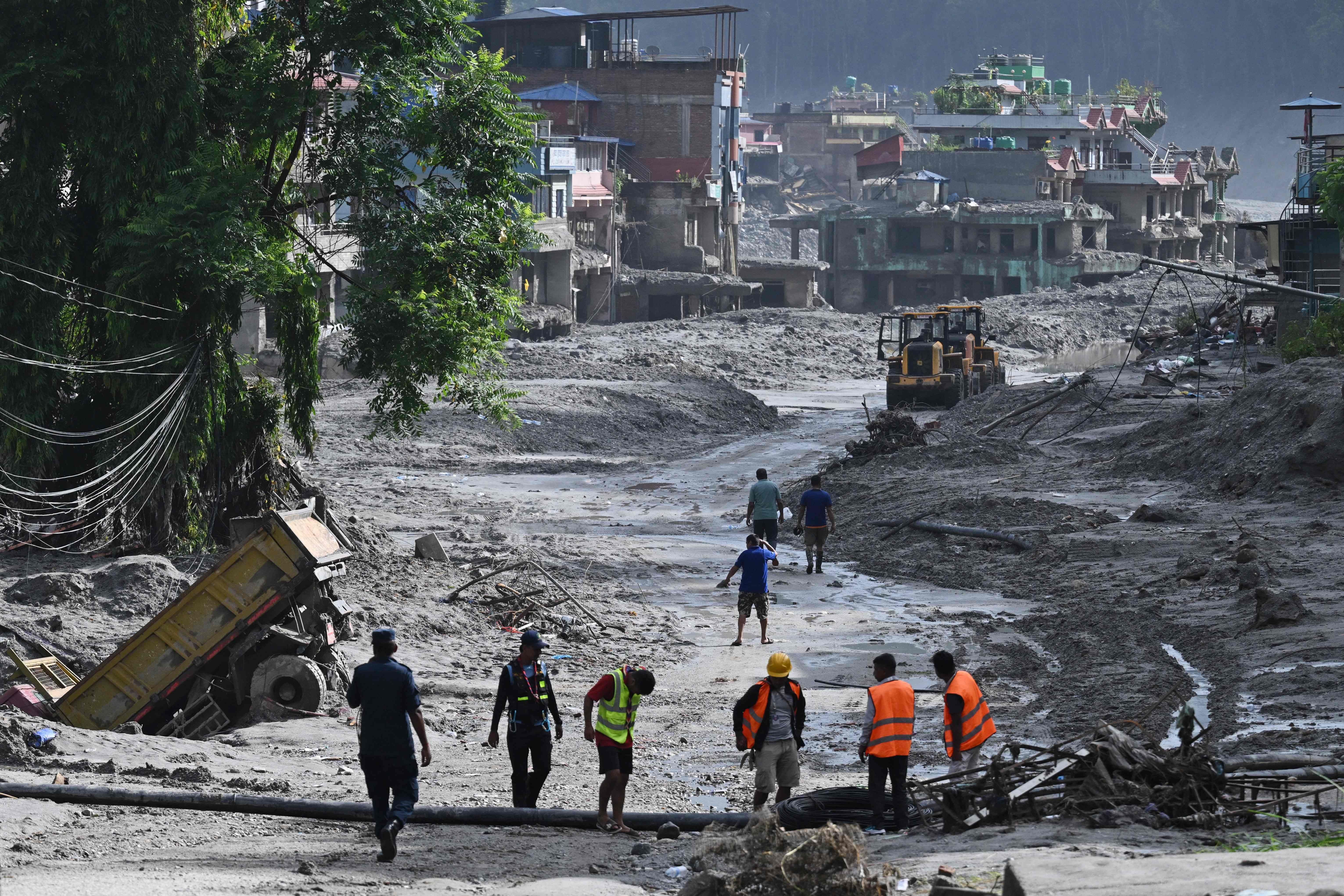Rettungskräfte suchen nach einer Überschwemmung in Nepal in einer schlammigen, zerstörten Stadt.