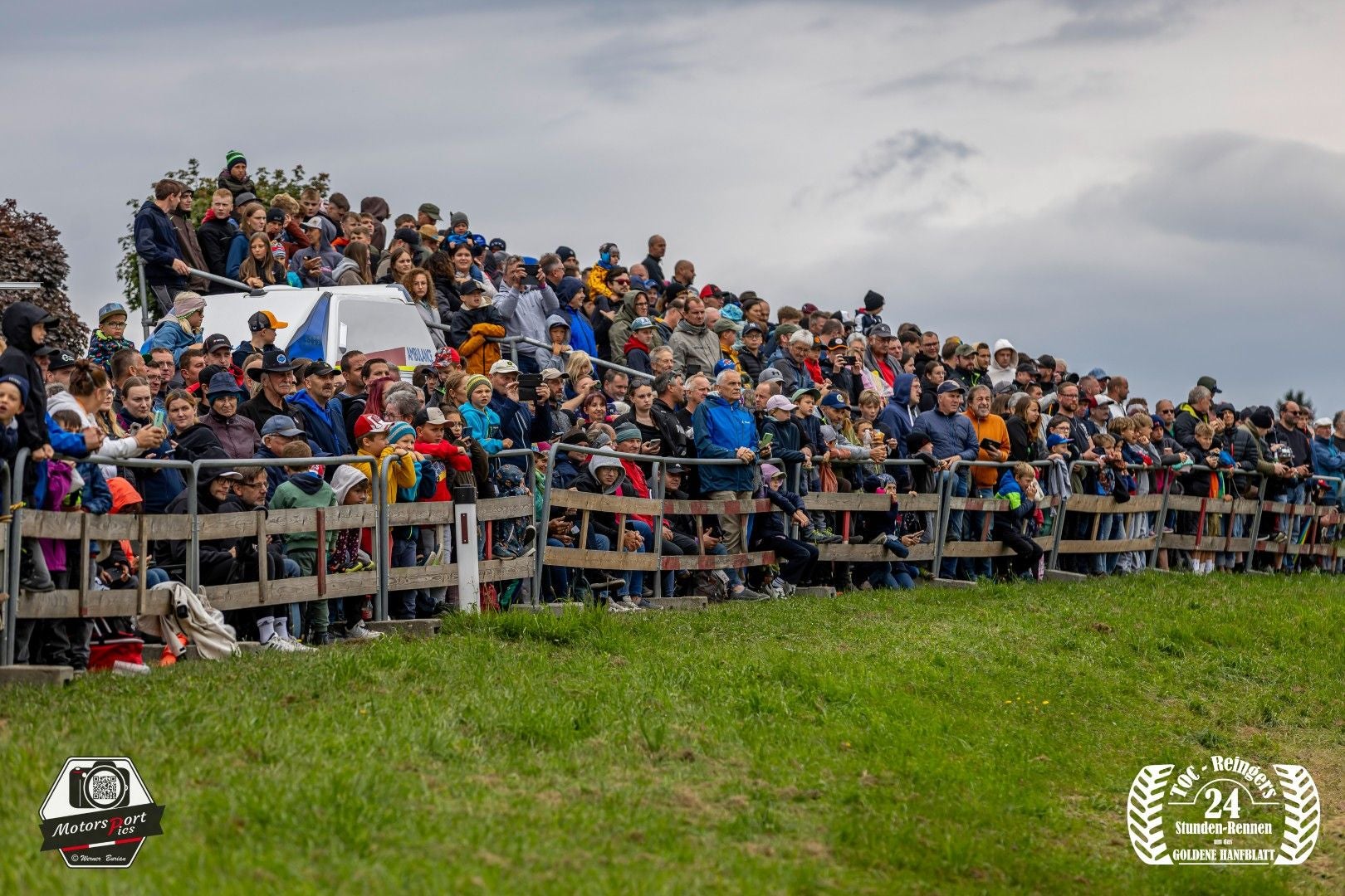 Viele Zuschauer stehen dicht gedrängt hinter einem Zaun bei einem Traktorrennen in Reingers.