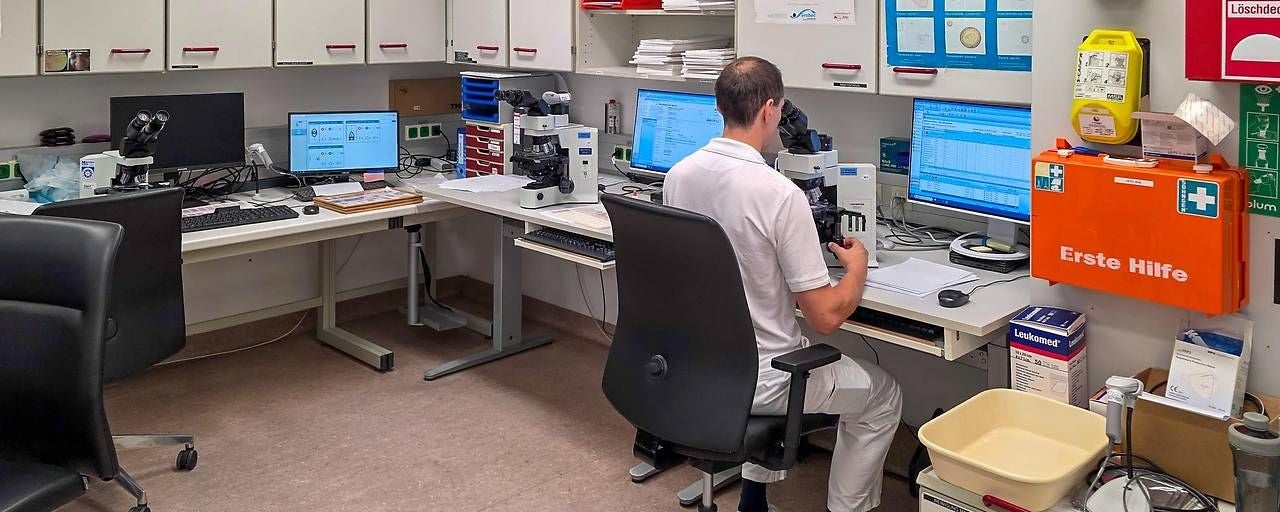 Ein Mann arbeitet mit einem Mikroskop in einem modern ausgestatteten Laborraum.