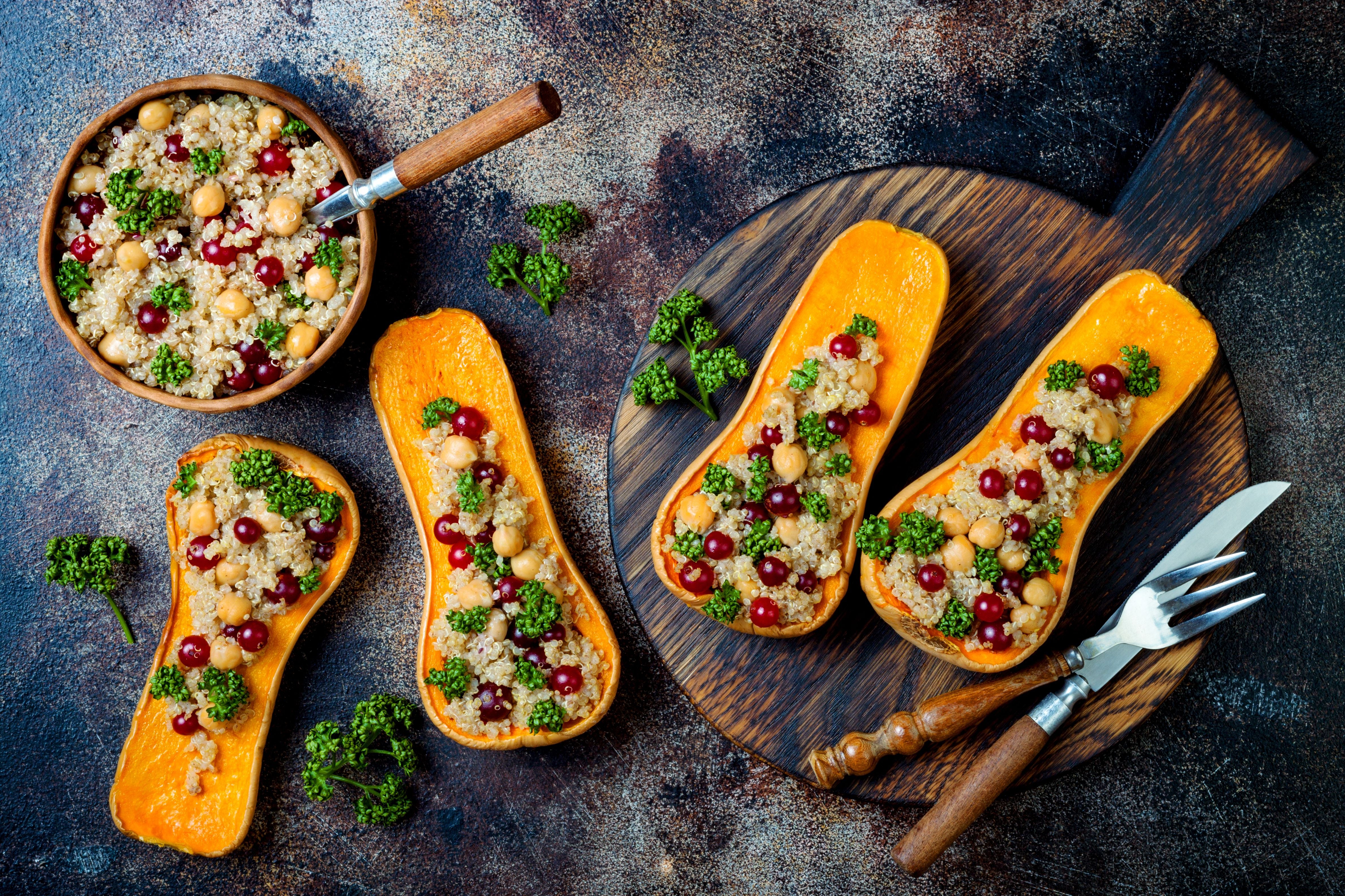 Gefüllter Butternut-Kürbis mit Kichererbsen, Cranberries, Quinoa und Kräutern auf einem Holzbrett.