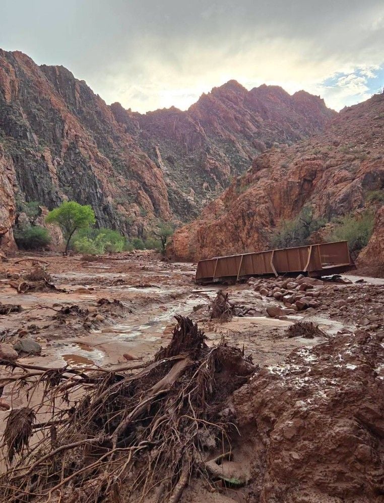 Schlammige Schlucht im Grand Canyon mit entwurzelten Bäumen und umgestürztem Waggon nach Sturzflut.