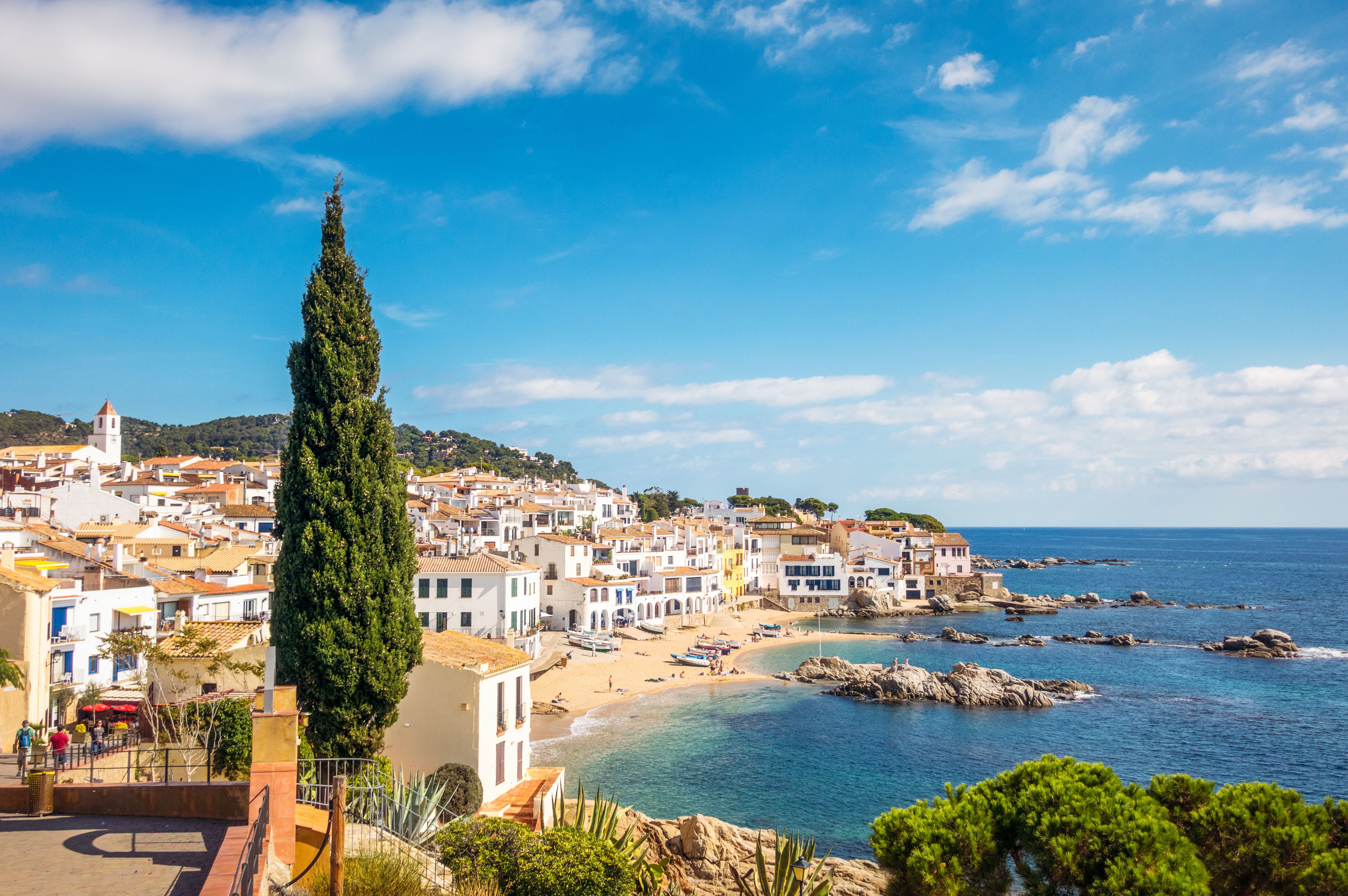 Blick auf Calella de Palafrugell mit weißen Häusern am Meer und einer kleinen Sandbucht.
