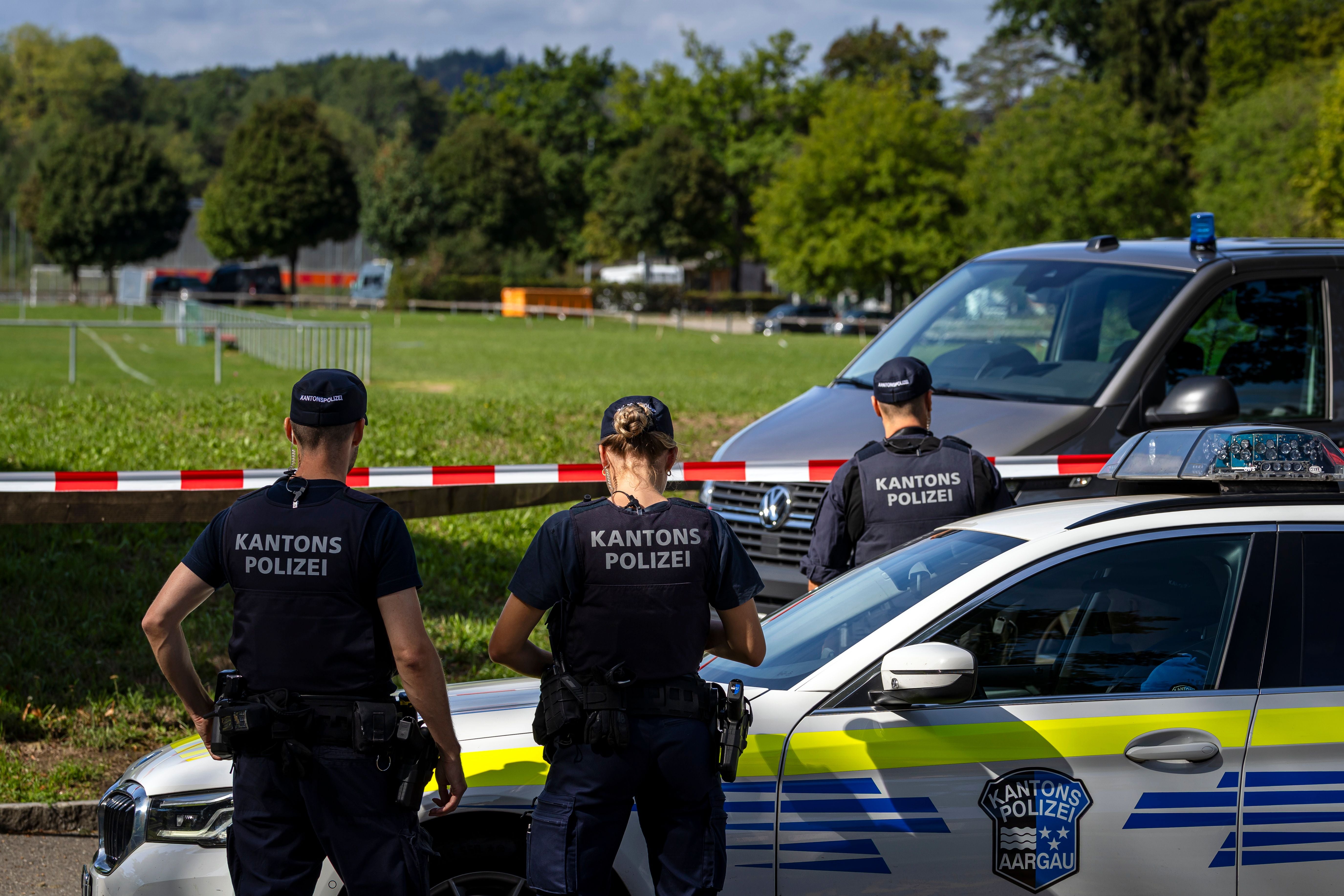 Drei Polizisten der Kantonspolizei Aarau sichern ein abgesperrtes Gelände mit Einsatzfahrzeugen.