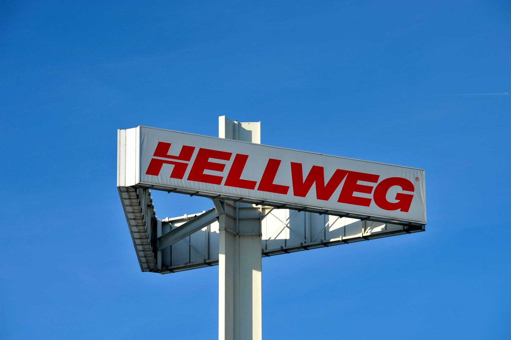 Großes Hellweg-Baumarkt-Schild mit roter Schrift vor blauem Himmel in Berlin.