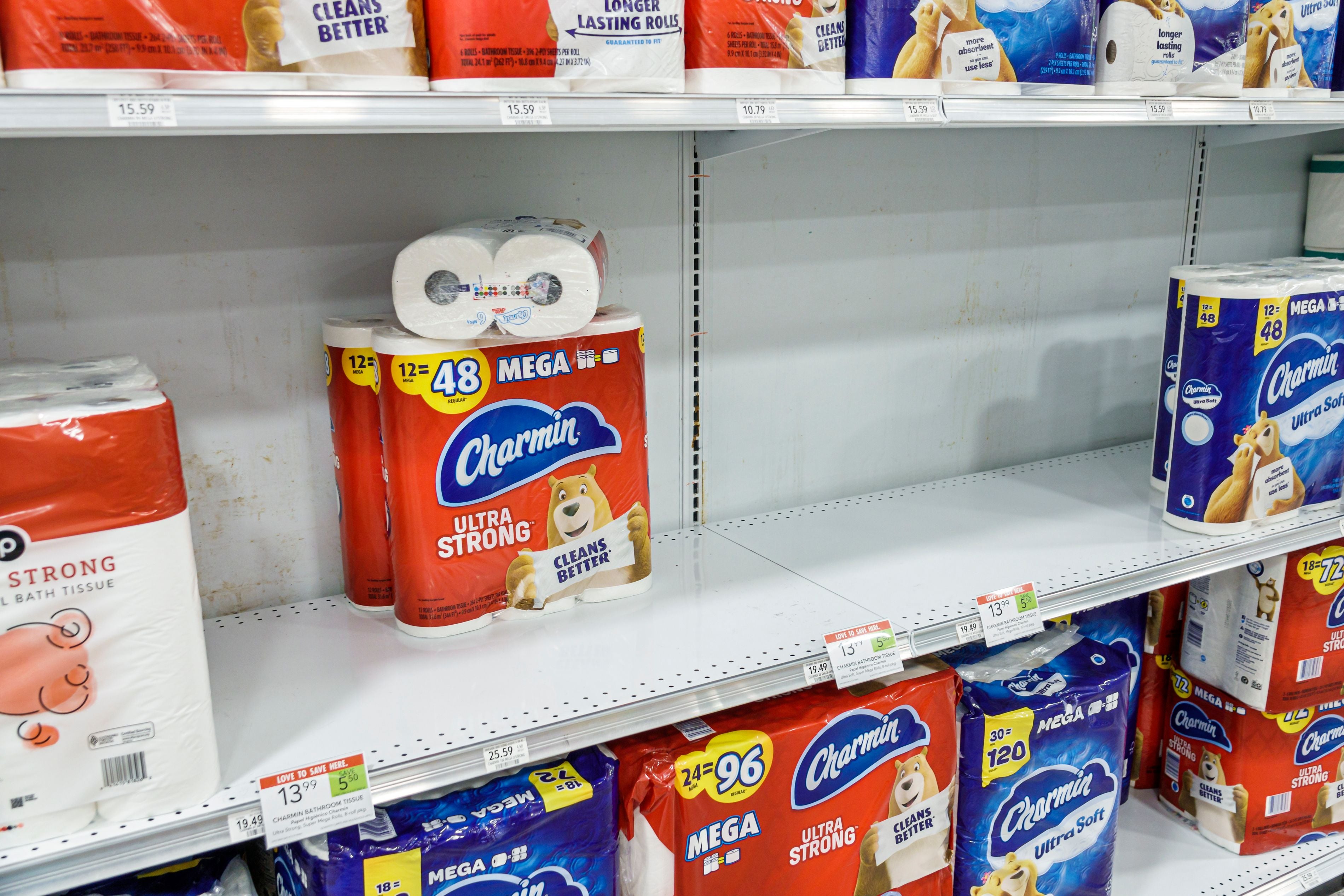 Leere Regale mit wenigen Packungen Charmin-Toilettenpapier in einem Supermarkt.