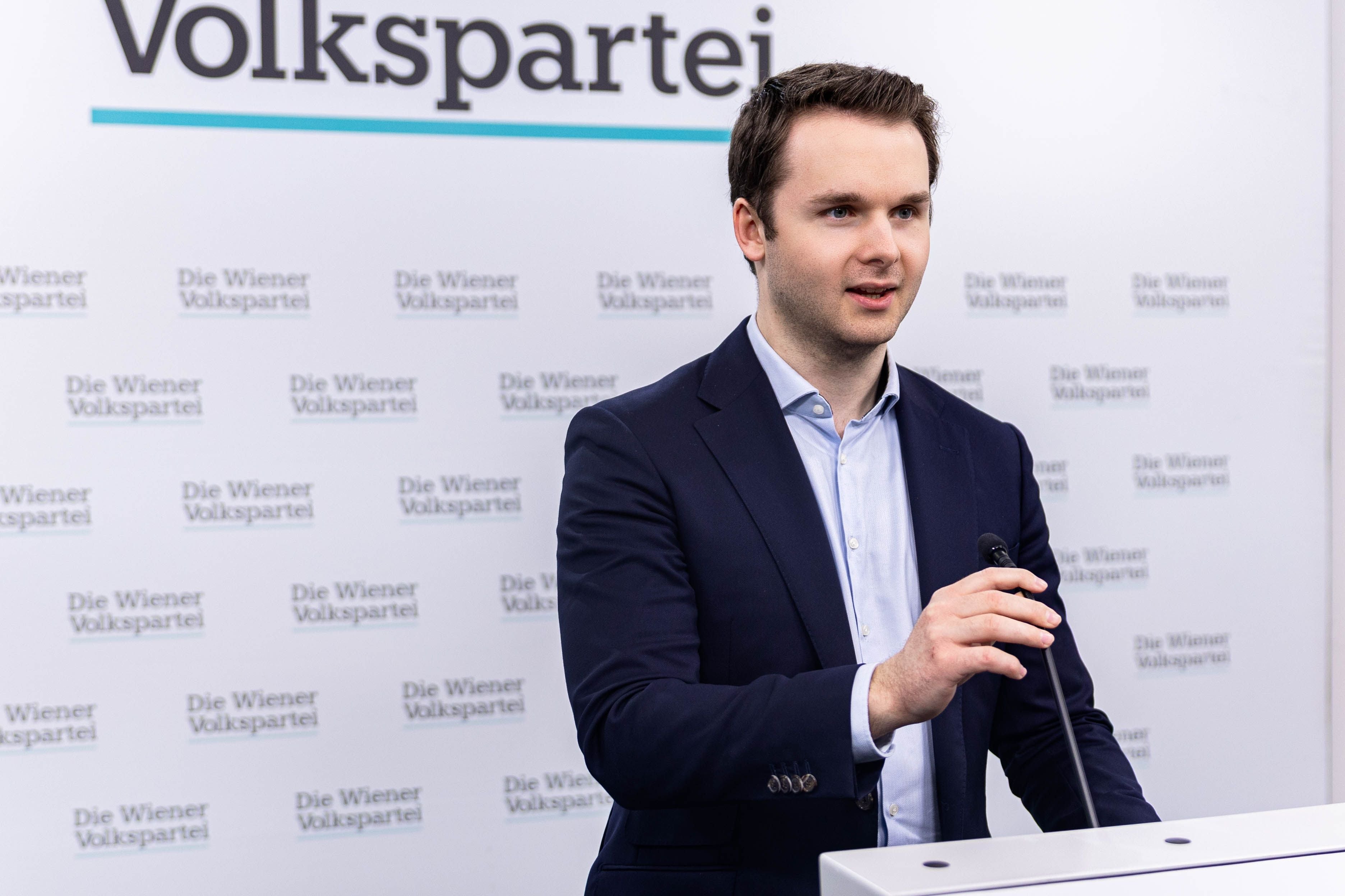 Mann im Anzug spricht an einem Rednerpult mit Mikrofon vor Hintergrund „Die Wiener Volkspartei“.