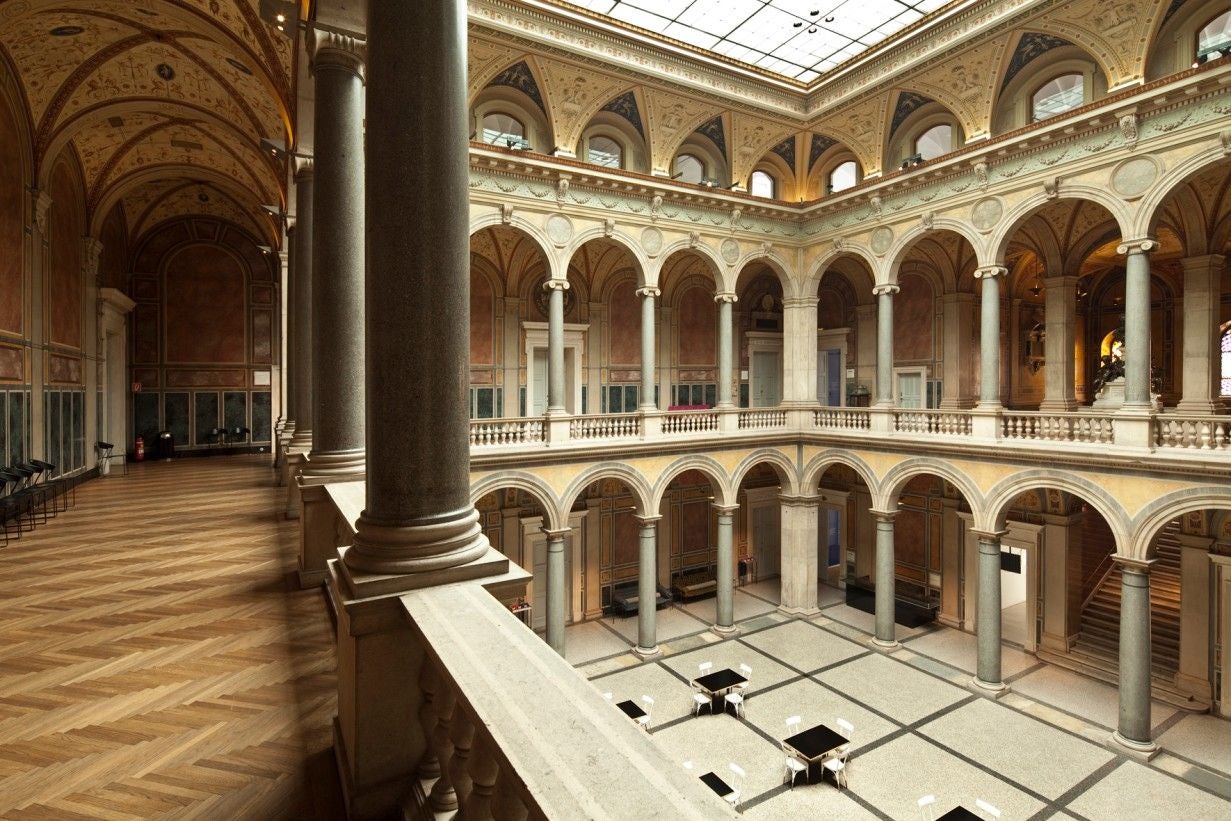 Blick in den lichtdurchfluteten Innenhof des MAK Museums mit Arkaden und Marmorsäulen.