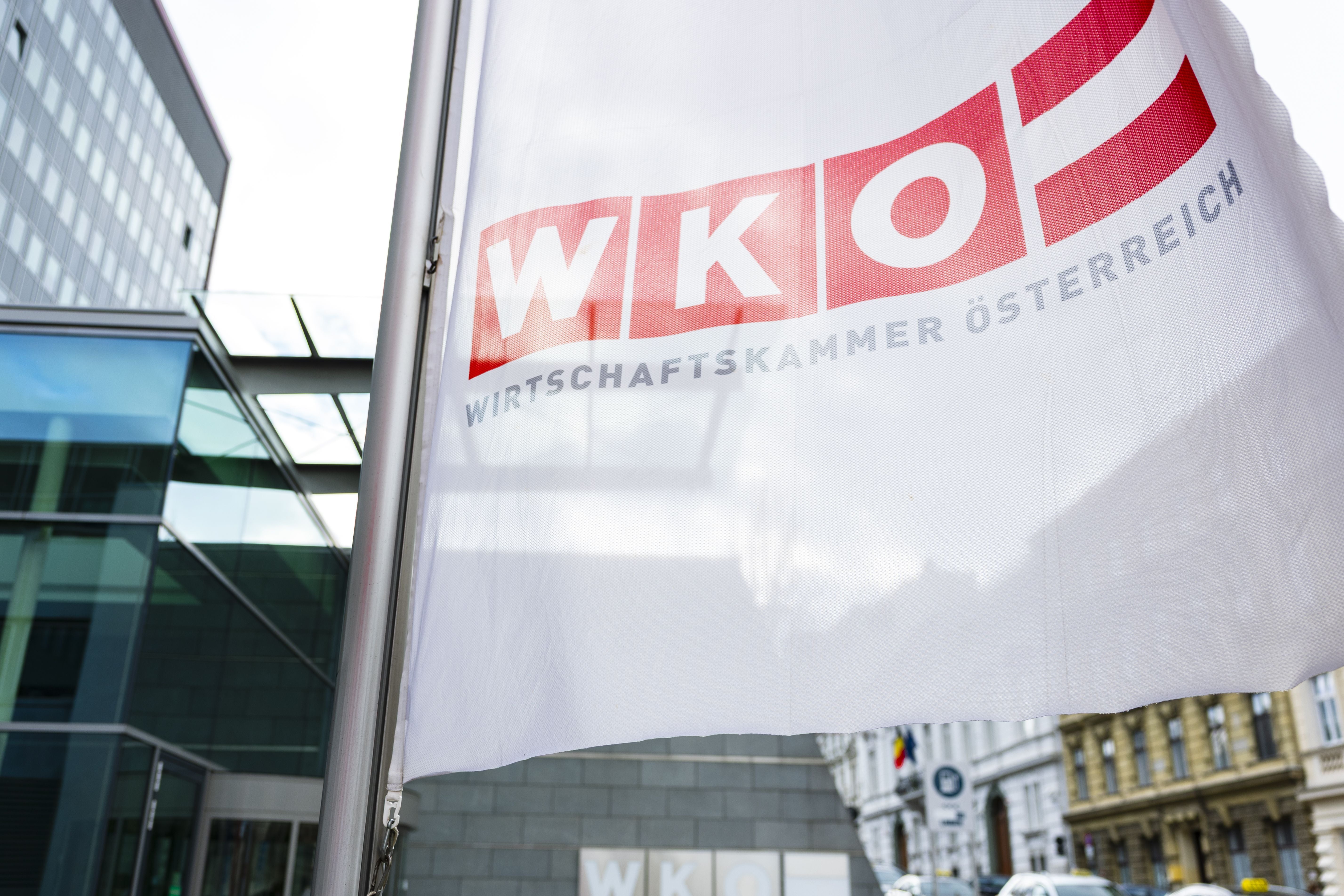 Weiße Fahne mit rotem WKÖ-Logo vor modernen Gebäuden in Wien.