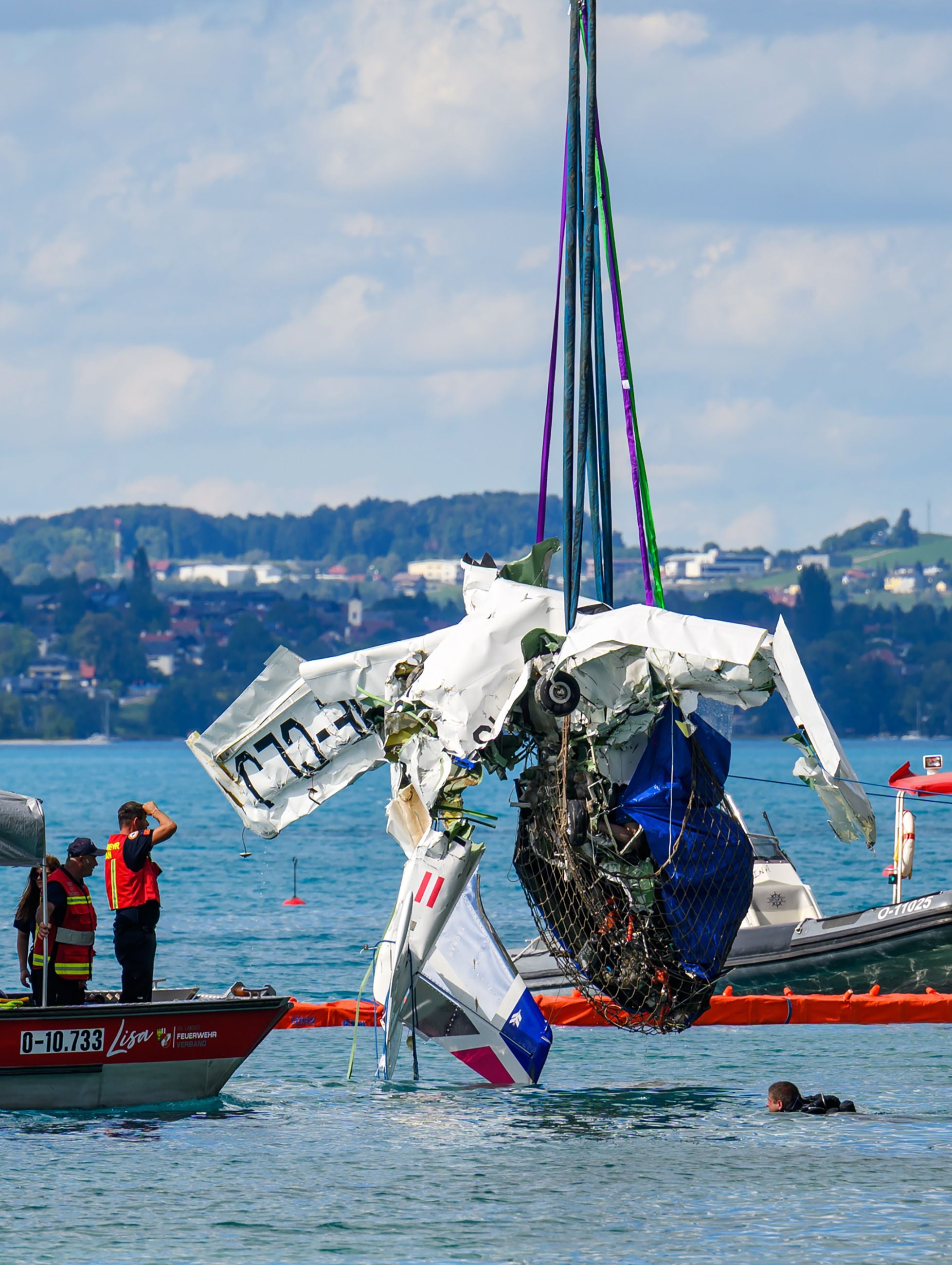 Bergung eines zerschellten Propellerflugzeugs aus dem Attersee durch Einsatzkräfte und Taucher.