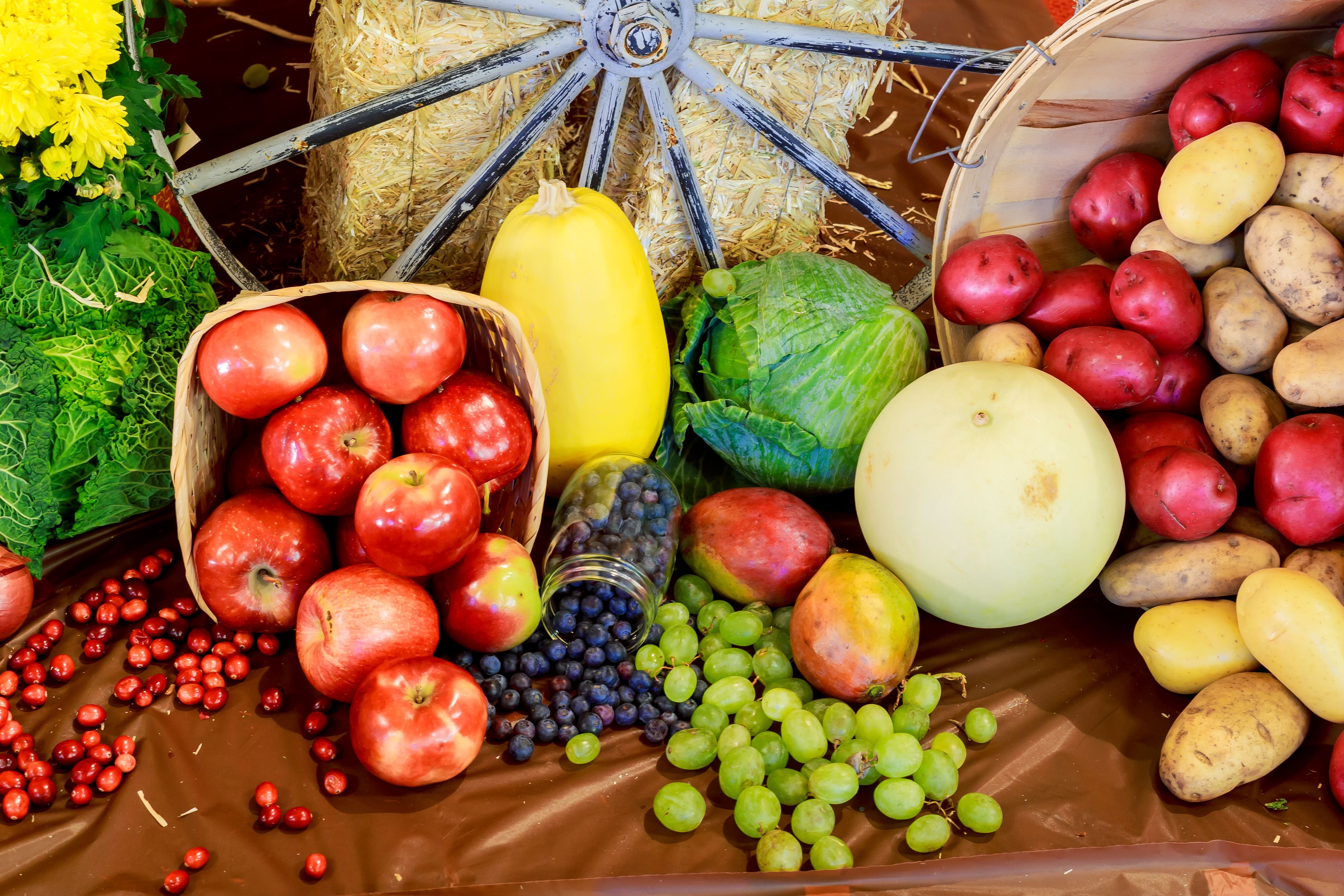 Verschiedene Obst- und Gemüsesorten liegen dekorativ zusammen, darunter Äpfel, Trauben und Kartoffeln.