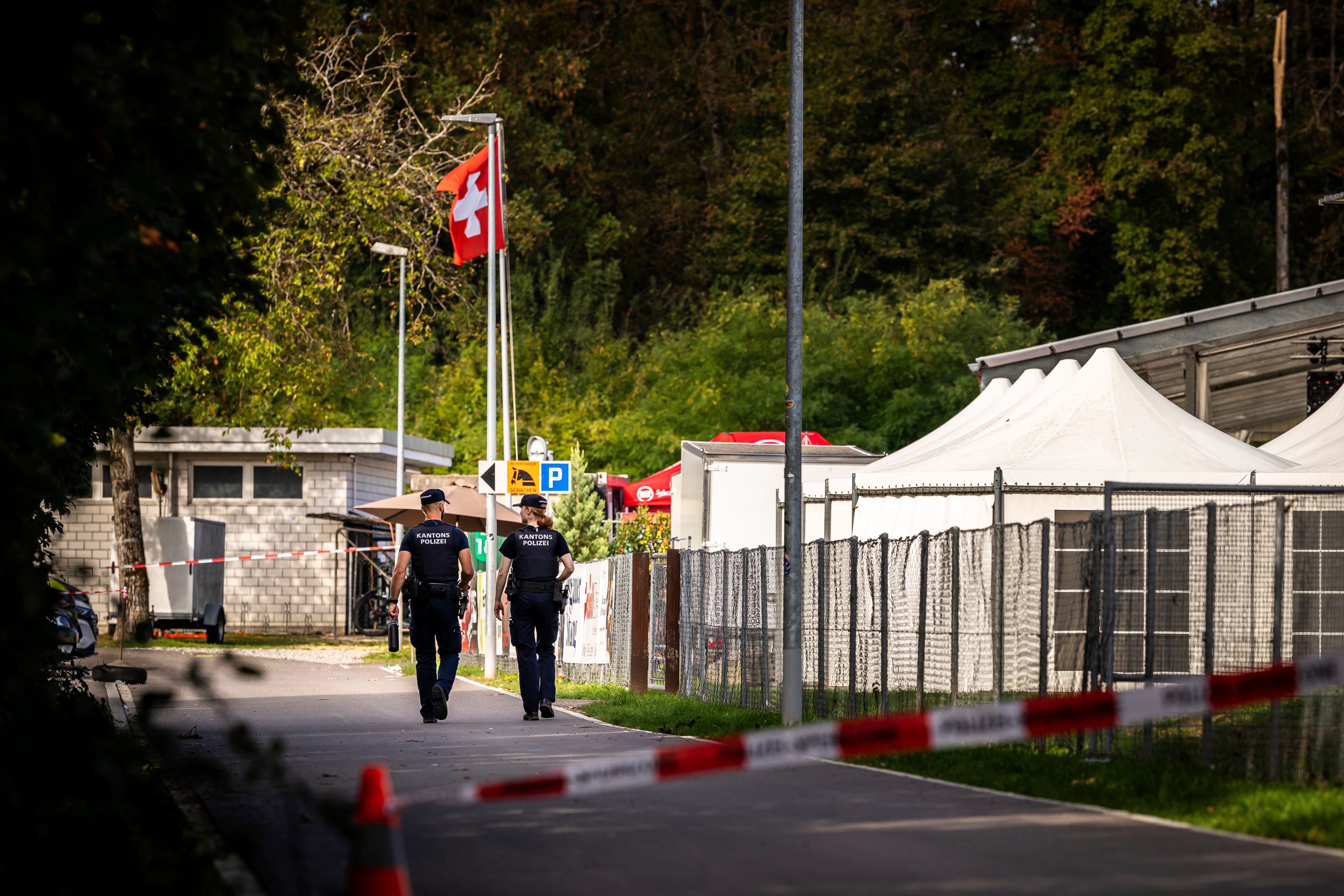 Zwei Polizisten patrouillieren hinter einer Absperrung an einem Pferderennplatz in der Schweiz.