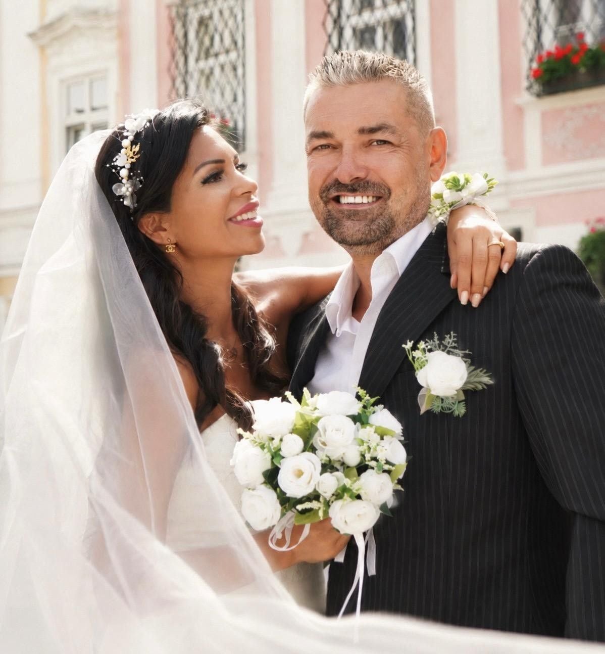 Braut und Bräutigam lächeln glücklich bei ihrer Hochzeit, die Braut hält einen Blumenstrauß.