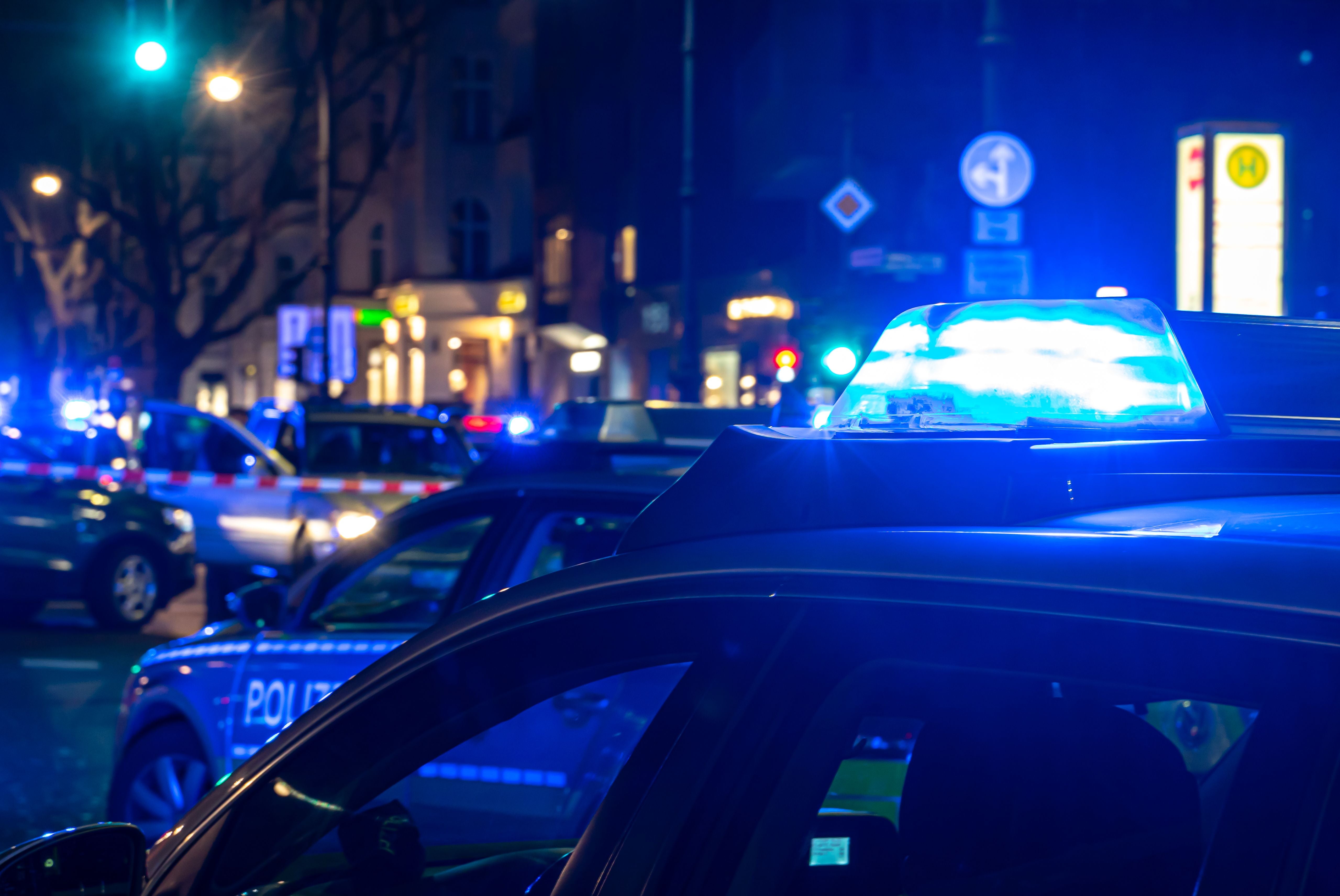 Mehrere Polizeiautos mit Blaulicht in einer Stadt bei Nacht.